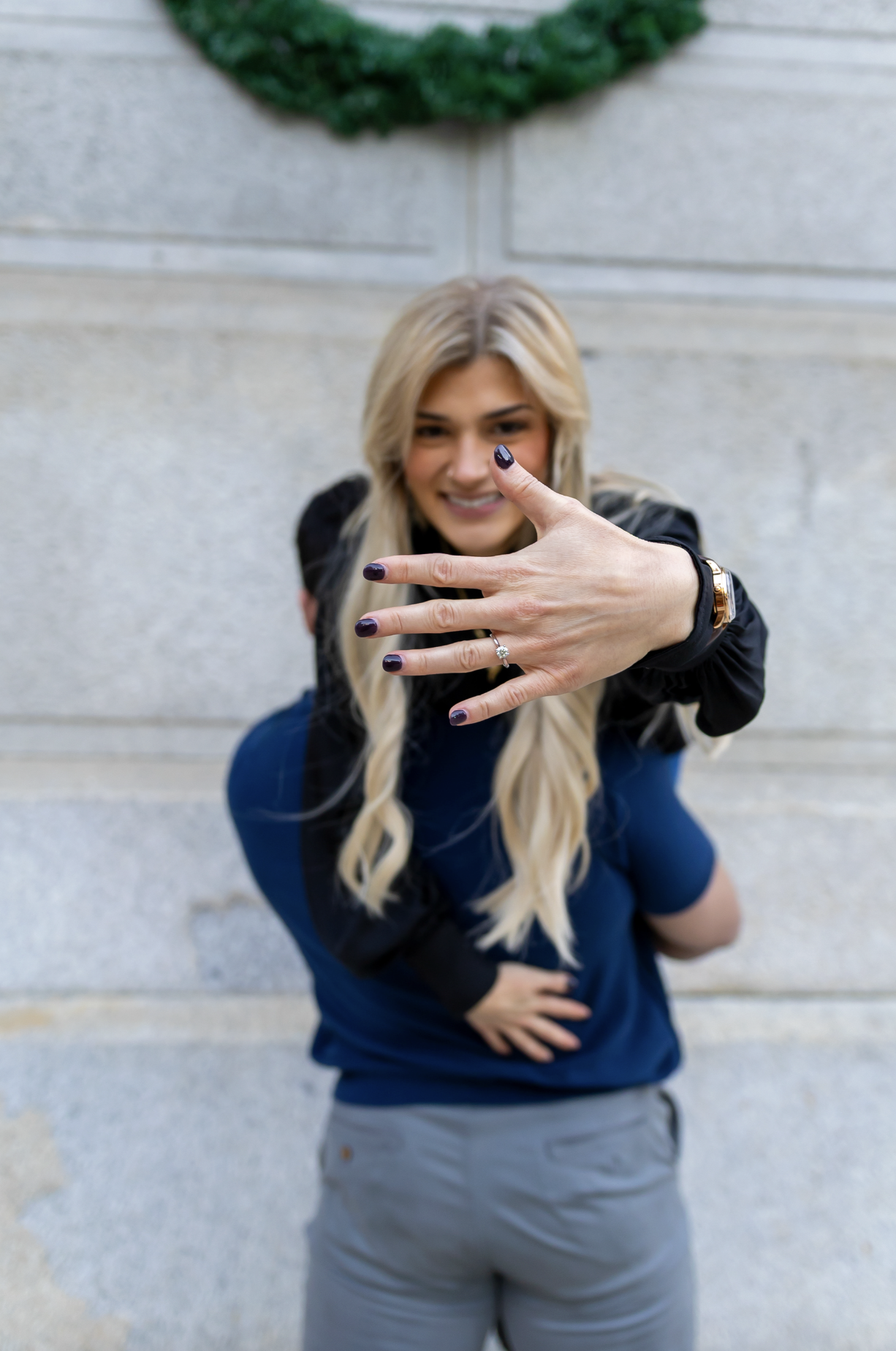 A smiling woman showing her ring to the camera, in a fun, playful pose following an proposal in Philadelphia, Pennsylvania.