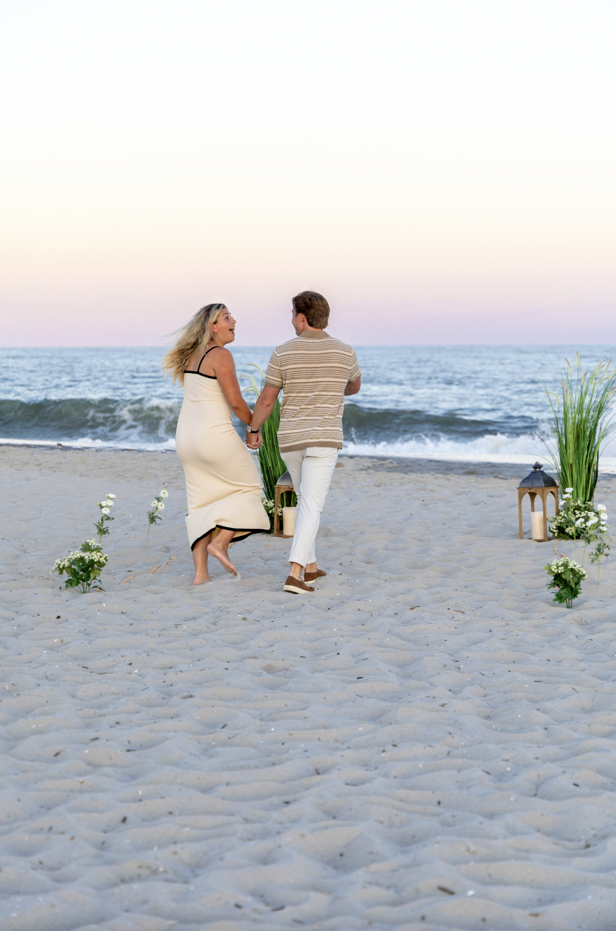 A couple walking to set up proposal on the beach, at sunset, in Cape May, New Jersey.
