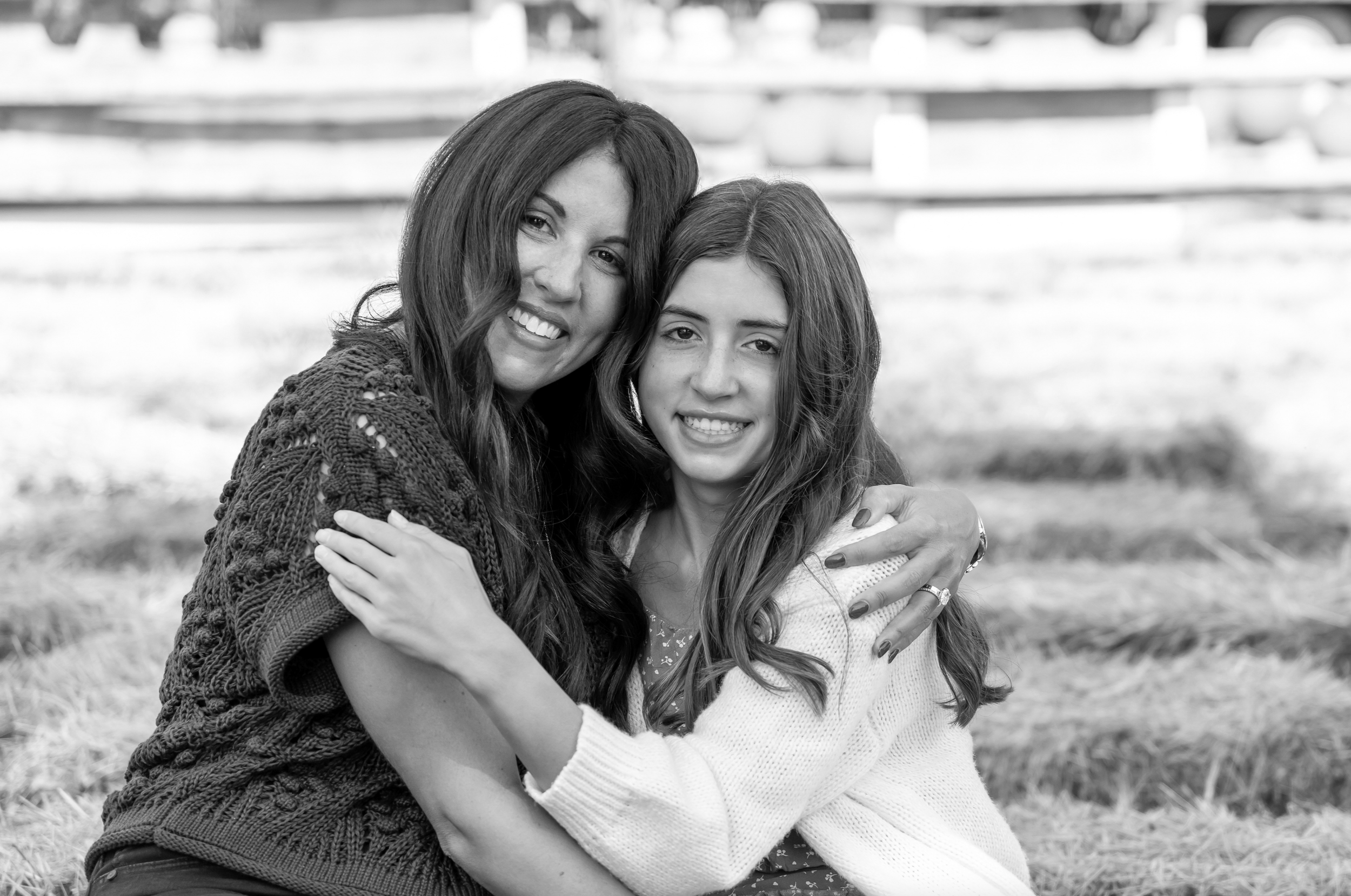 A woman and a girl hugging and smiling outdoors in a black and white photo. Carroll's Christmas Tree Farm, Lawrence, New Jersey