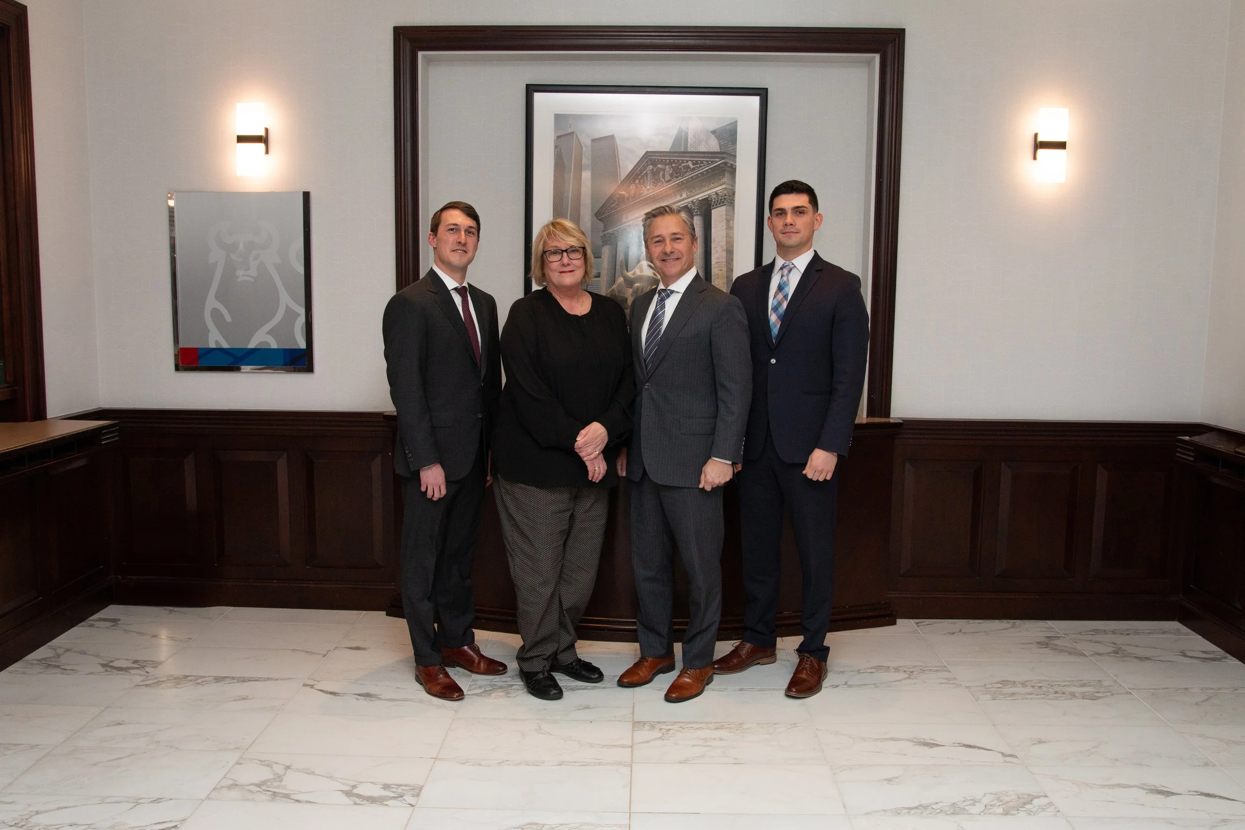 A group of four people standing in a conference room with wood paneling, marble floor, and framed artwork on the wall. Merrill Lynch Princeton, New Jersey