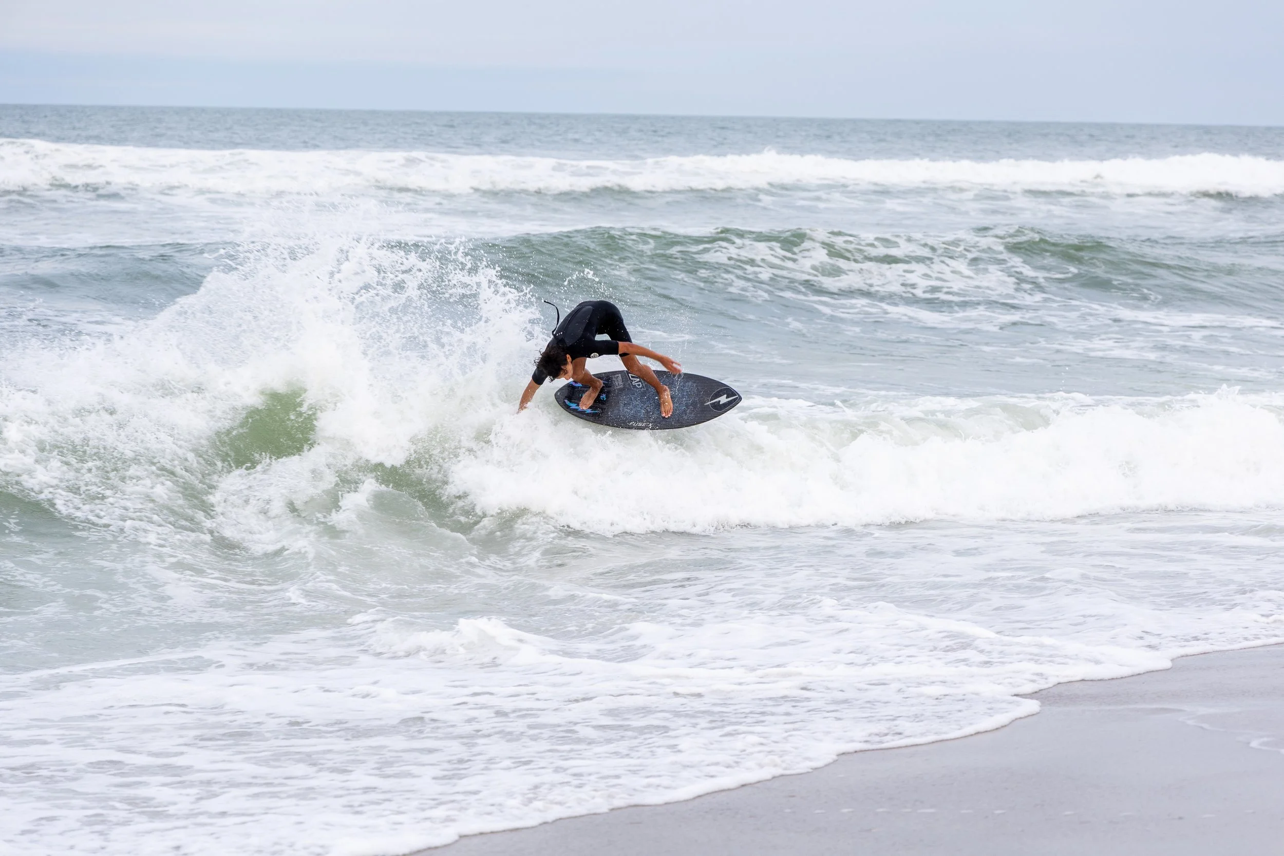 A person surfing on a wave at the beach.