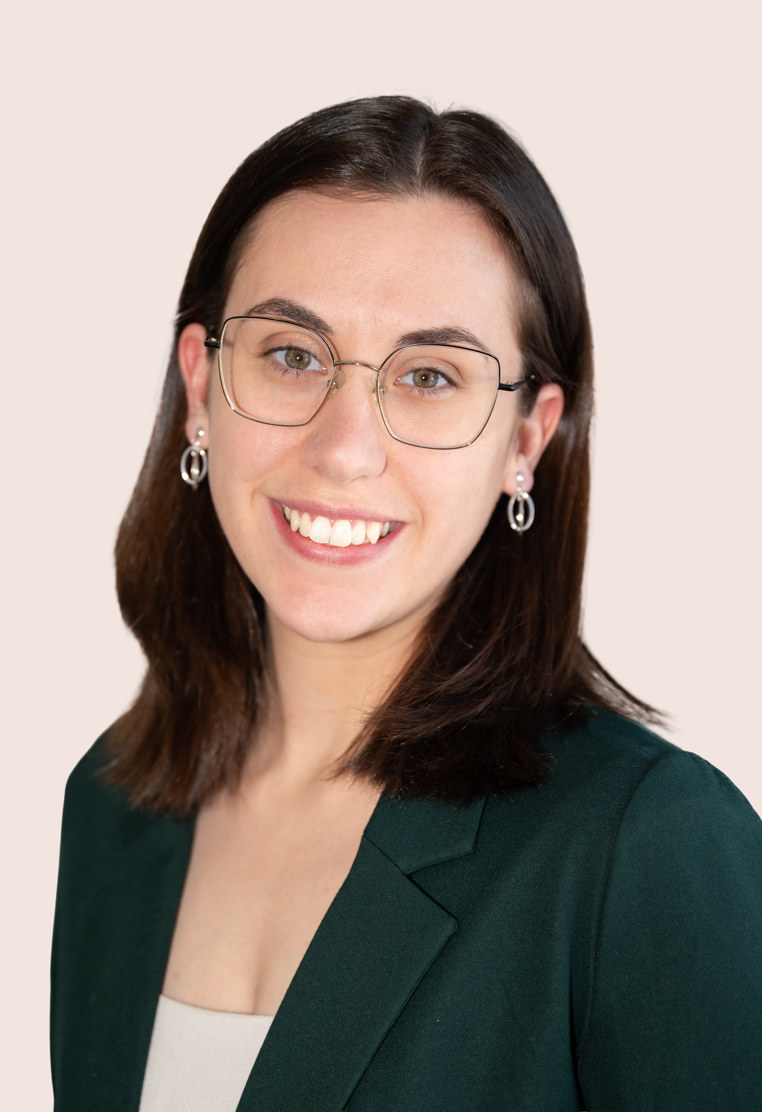 Portrait de Laurianne Cloutier, physiothépeute, souriante avec des lunettes, portant des boucles d'oreilles en argent et une veste verte, contre un fond neutre.