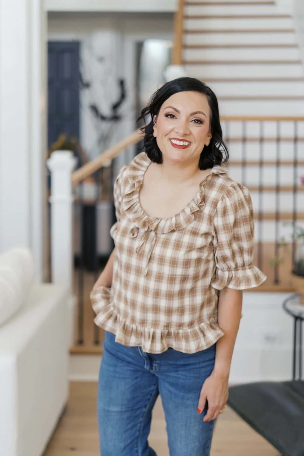 Dolly DeLong is a marketing coach, photographer, and host of the Systems and workflow magic podcast. She is standing and angled towards the camera and smiling with a checkered shirt and jeans on.