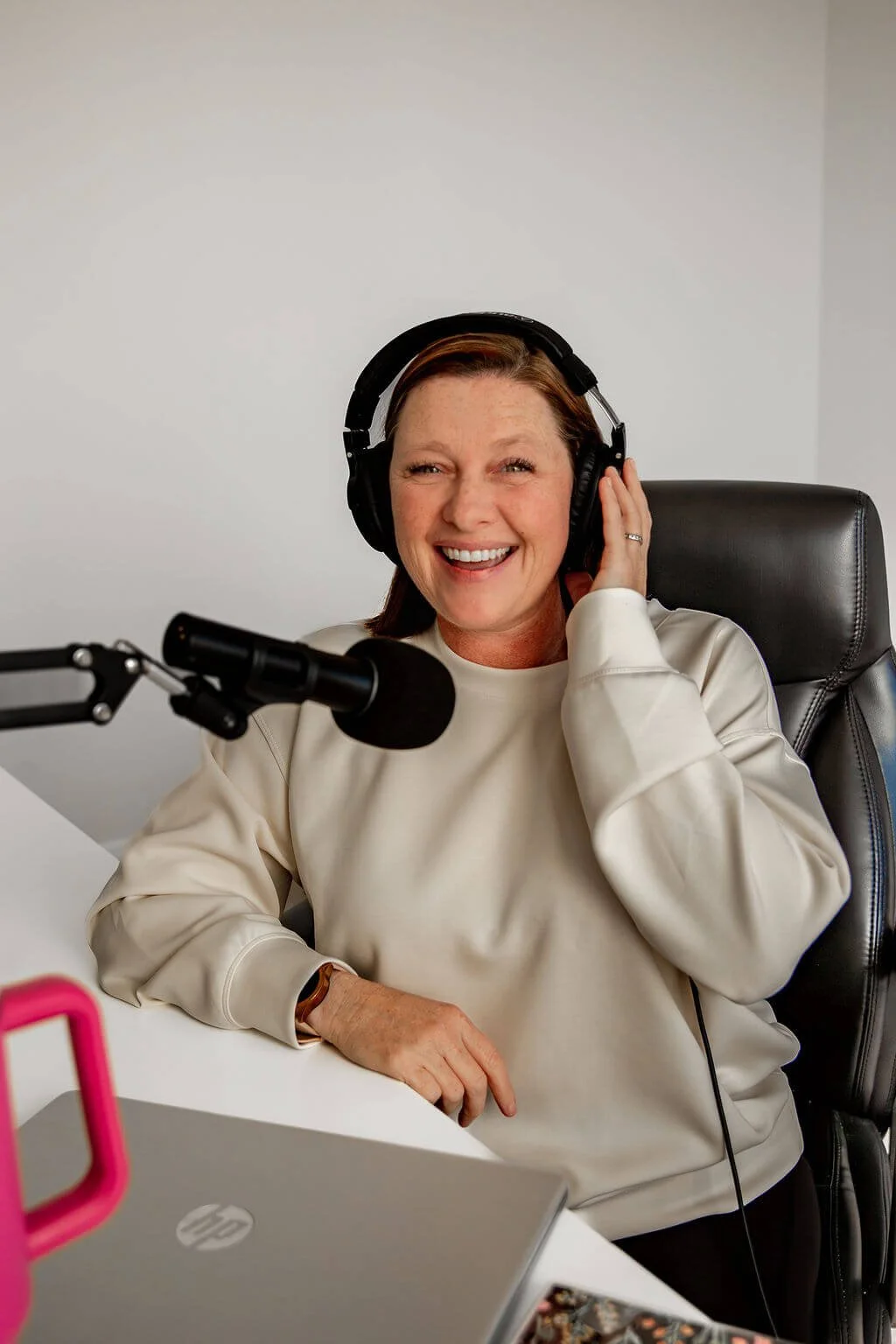 Liz Chapman a podcast producer smiling with headphones on her head and a microphone near her mouth
