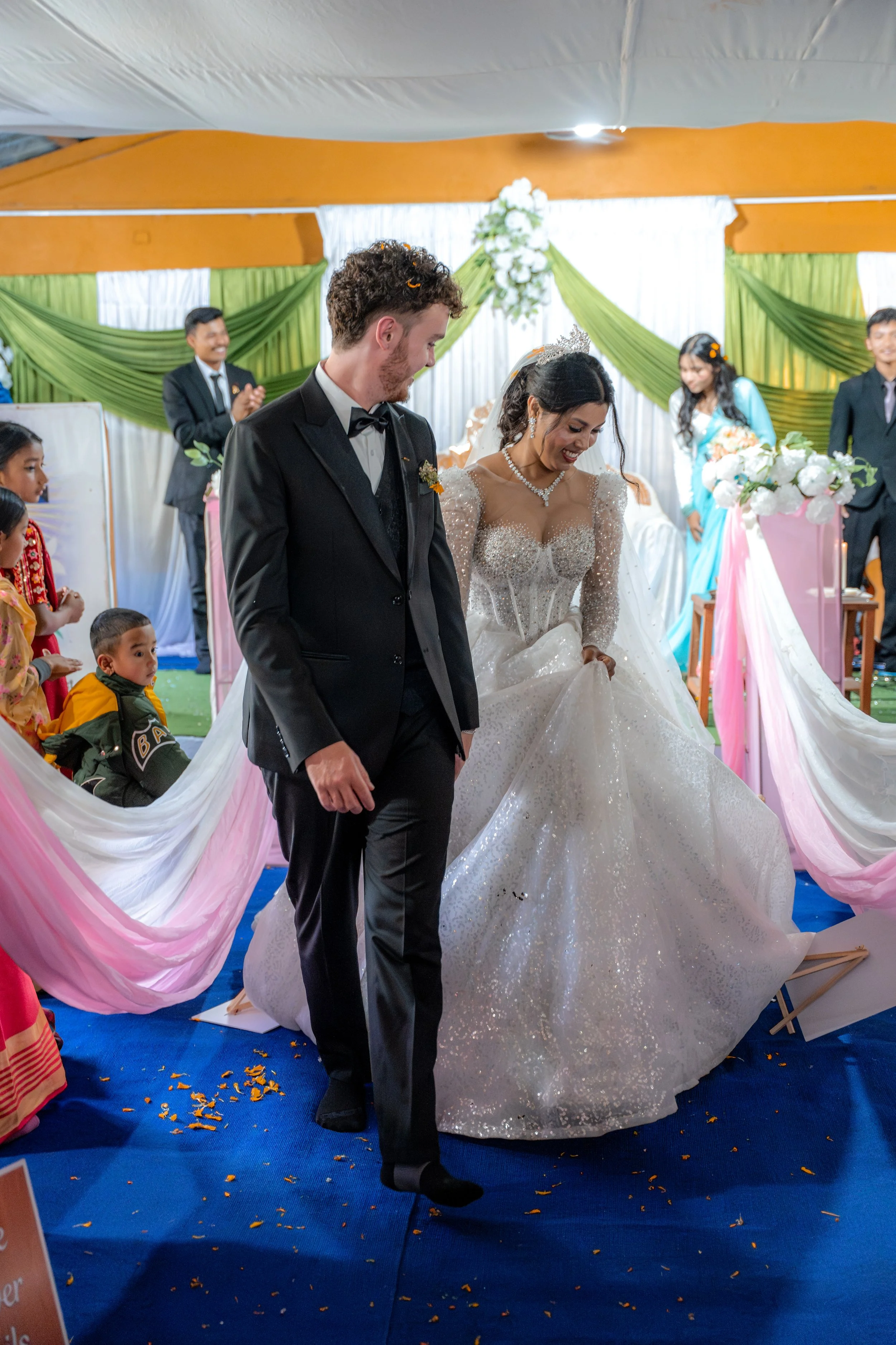 Bride and groom walking together during a wedding ceremony in a decorated hall.