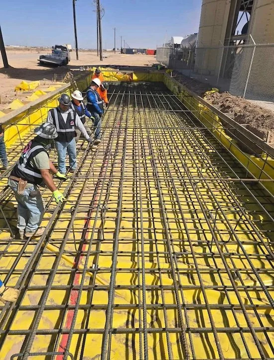 Construction workers installing rebar for concrete slab in a construction site.