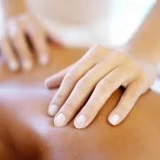 Close-up of a massage therapist's hands applying pressure to a person's back during a massage.