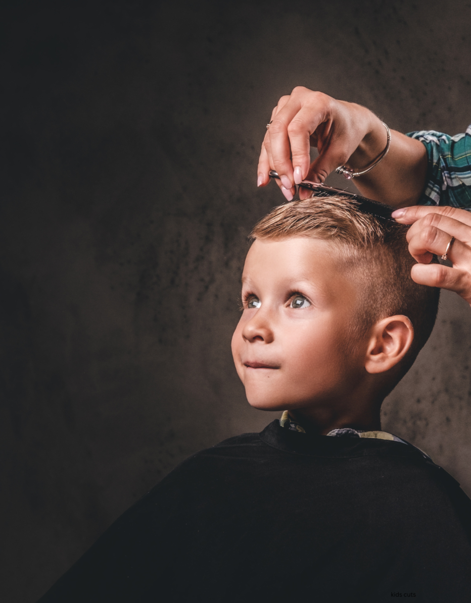 Young boy getting a haircut from a hairstylist in a salon or barbershop.