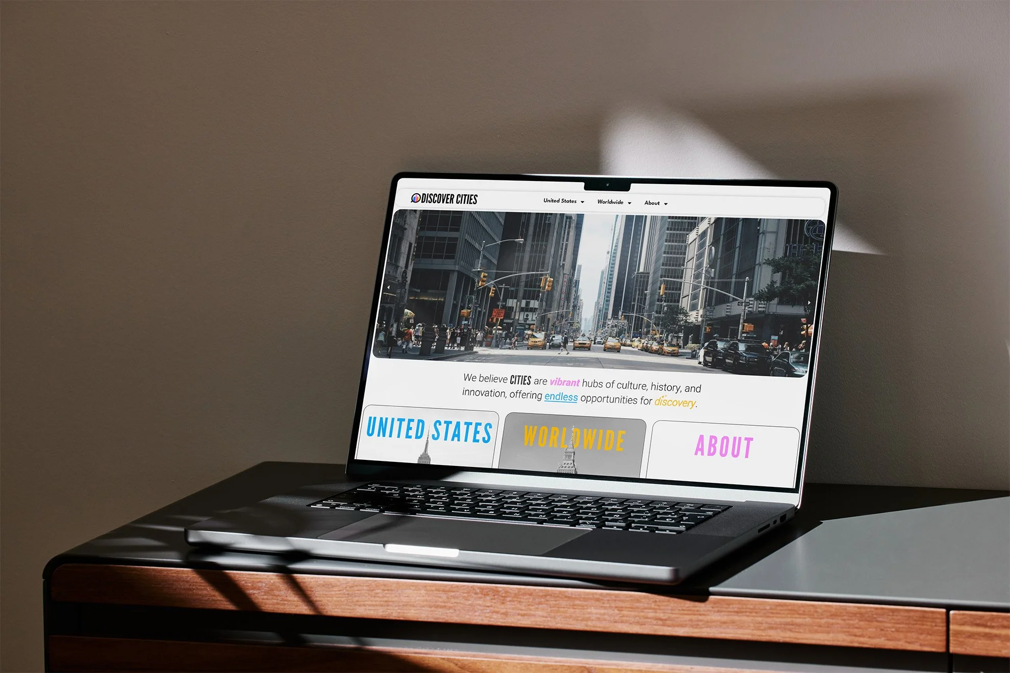 Laptop displaying a city travel website on a wooden table with sunlight casting shadows.