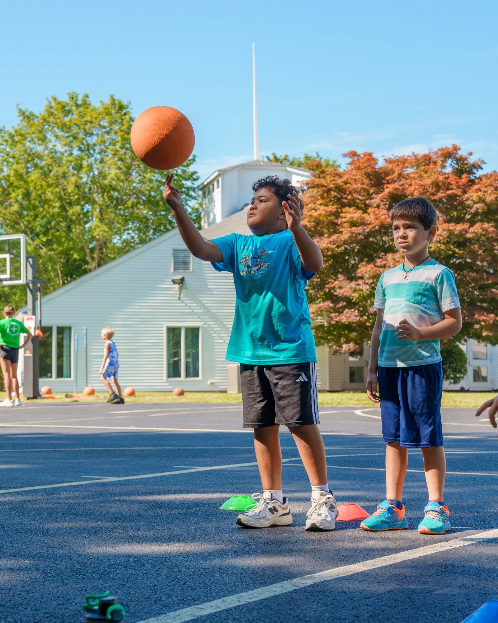Kids playing basketball outside on a sunny day.
