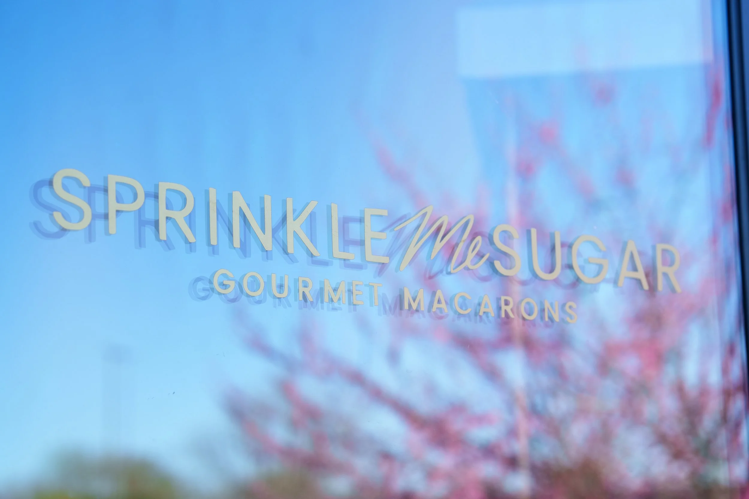 A window display advertising gourmet macarons with the text 'Springtime Sugar'.