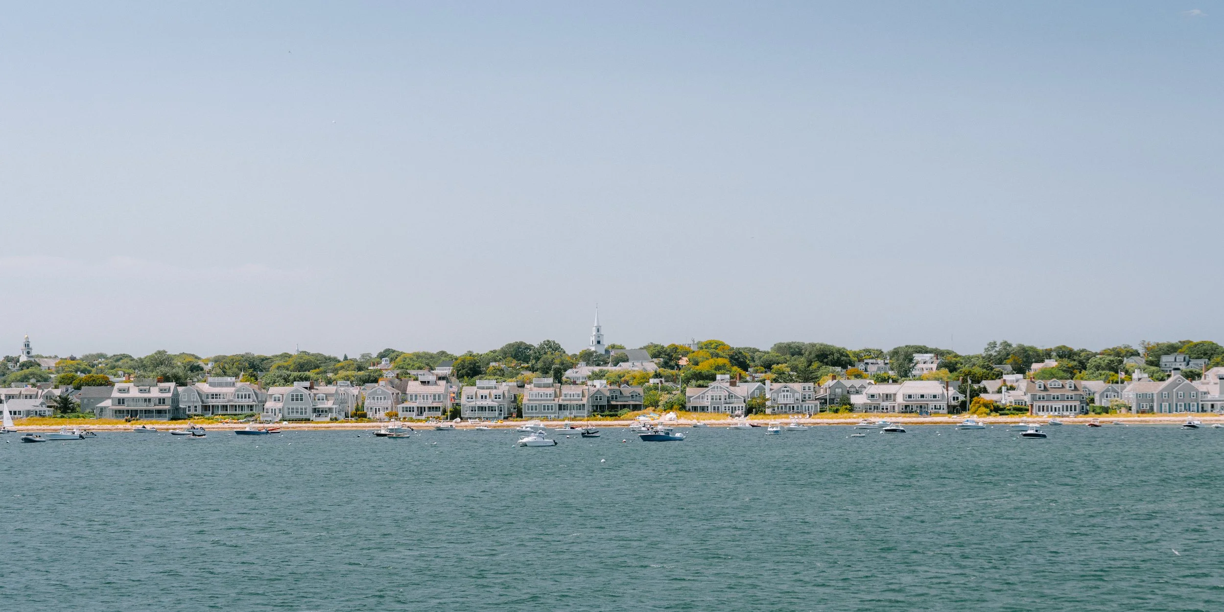 A coastal town with numerous houses and boats on the water, taken on a clear day.