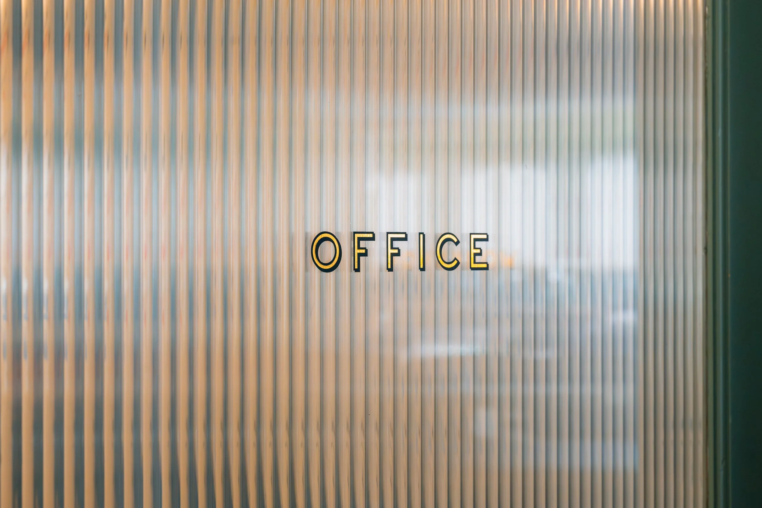 Office door with vertical blinds and a black and yellow sign saying 'OFFICE' in capital letters.