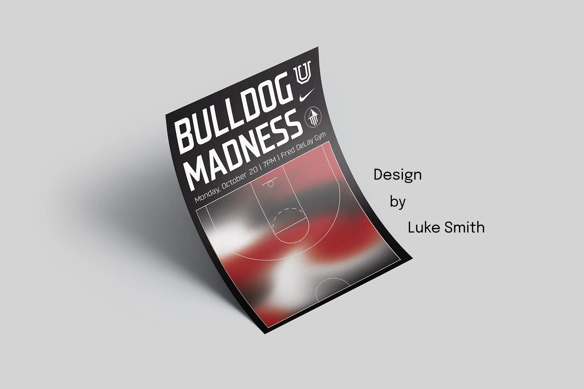A printed poster titled 'Bulldog Madness' with a basketball court graphic and event details, tilted on a gray surface. The poster includes logos of Nike, U, and other icons.