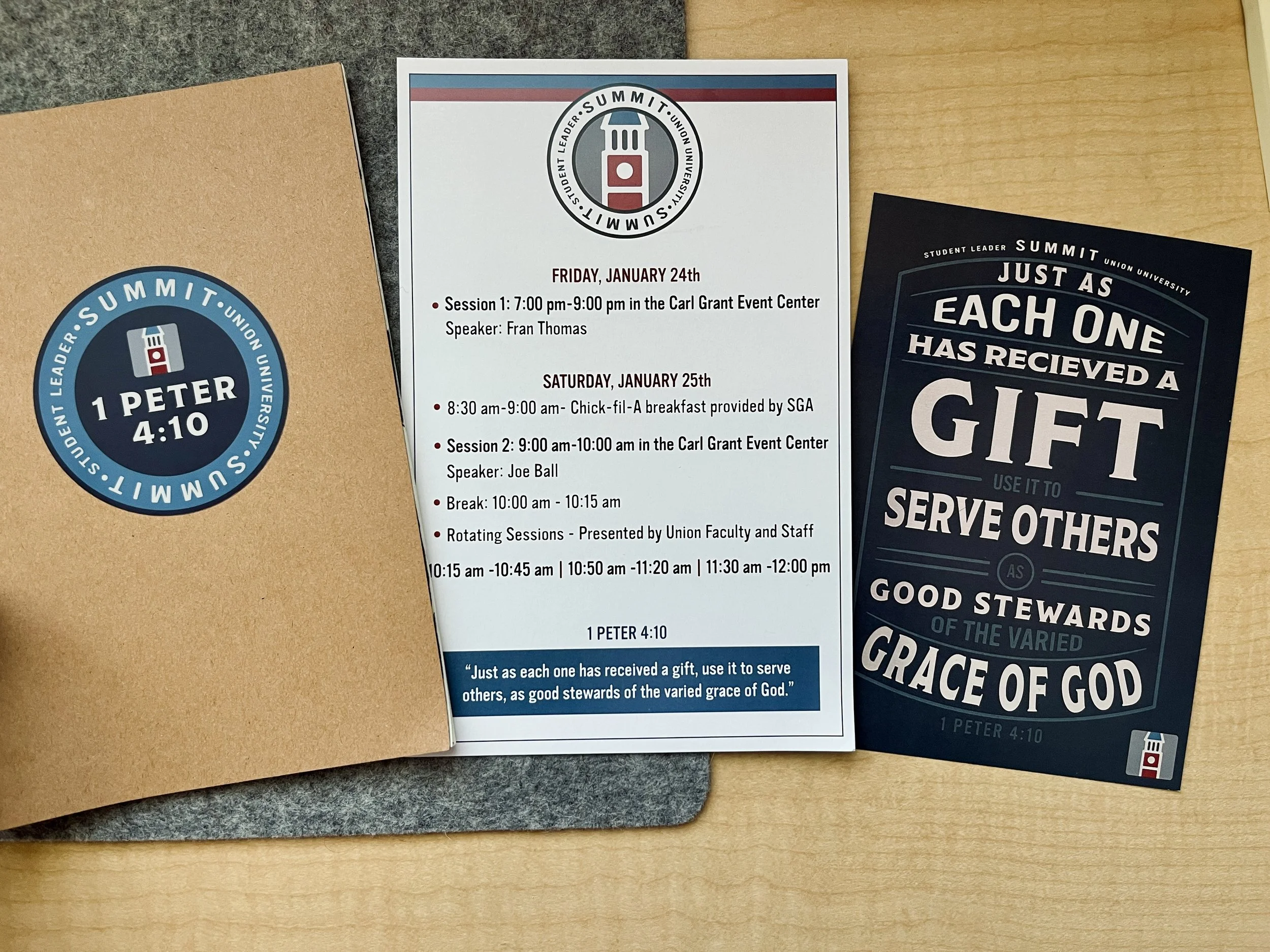 Three printed materials on a wooden surface and gray cloth, including a blue circular badge with the Union University logo and the text '1 Peter 4:10', a white schedule sheet with event details for a summit, and a navy blue flyer with motivational qu