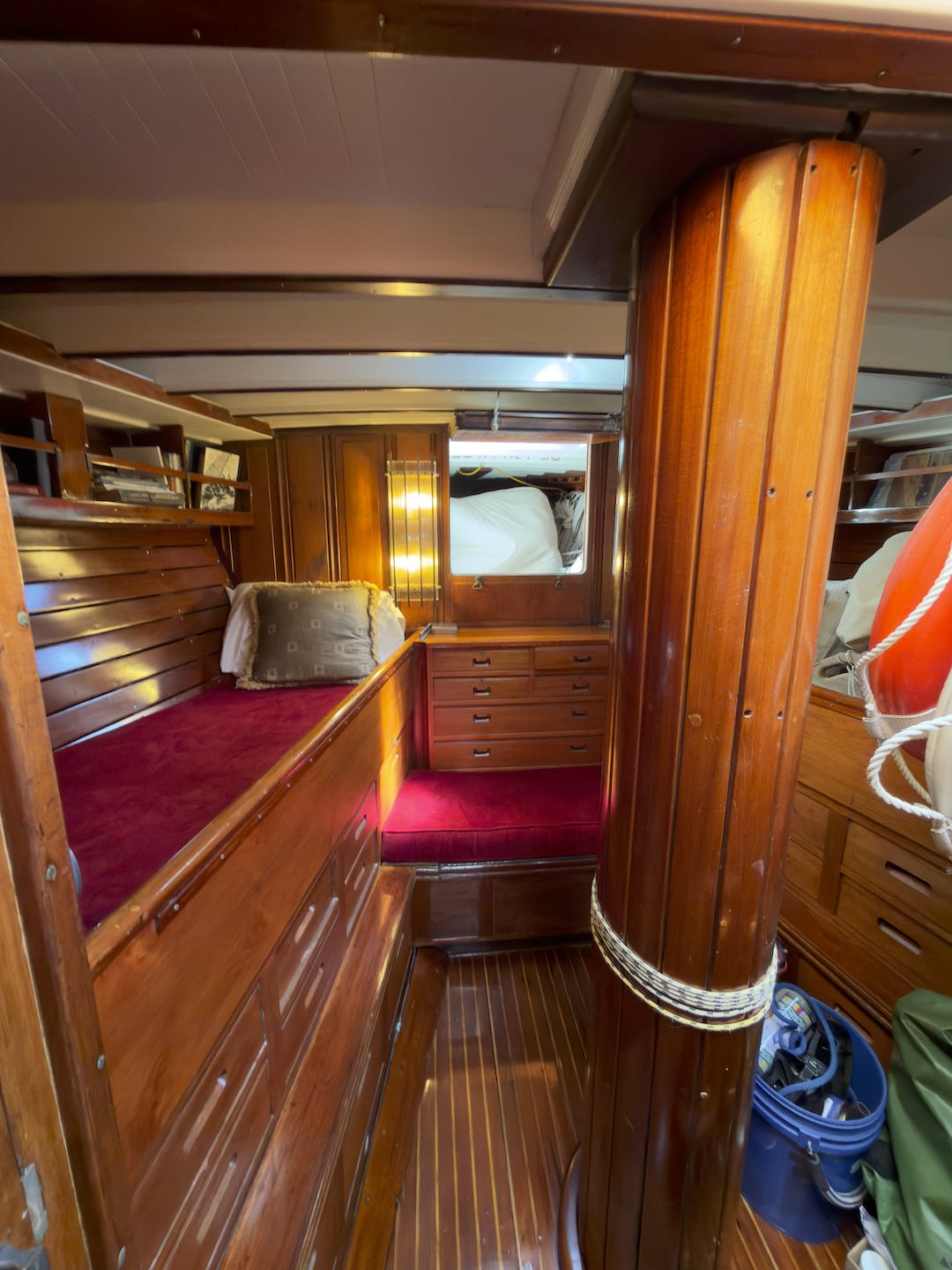 Interior of a wooden boat cabin with built-in seating, a mirror, and storage drawers.