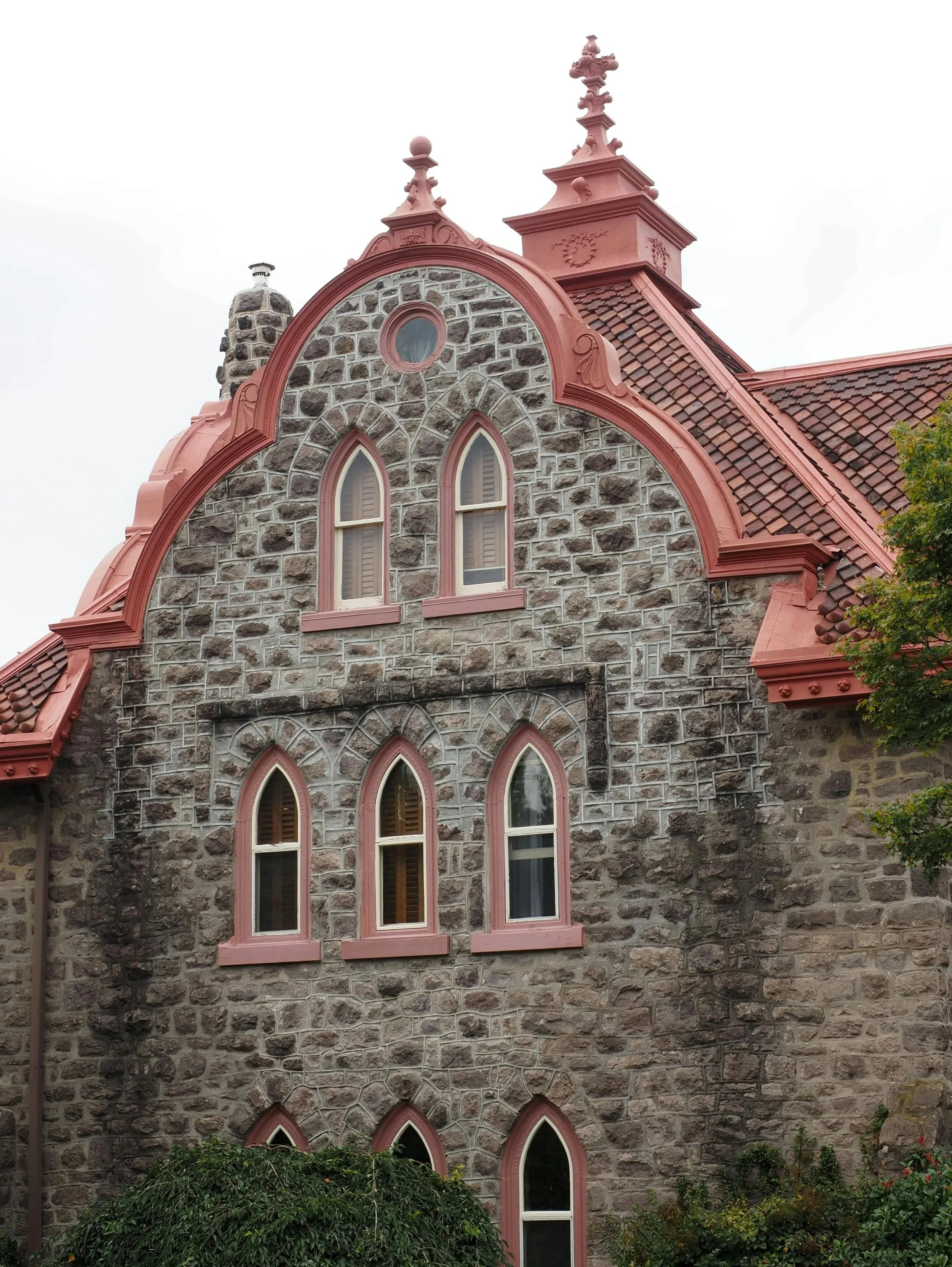 An historic Ambler, Pennsylvania home with stone exterior walls, decorative window panes and a pitched red slate roof.