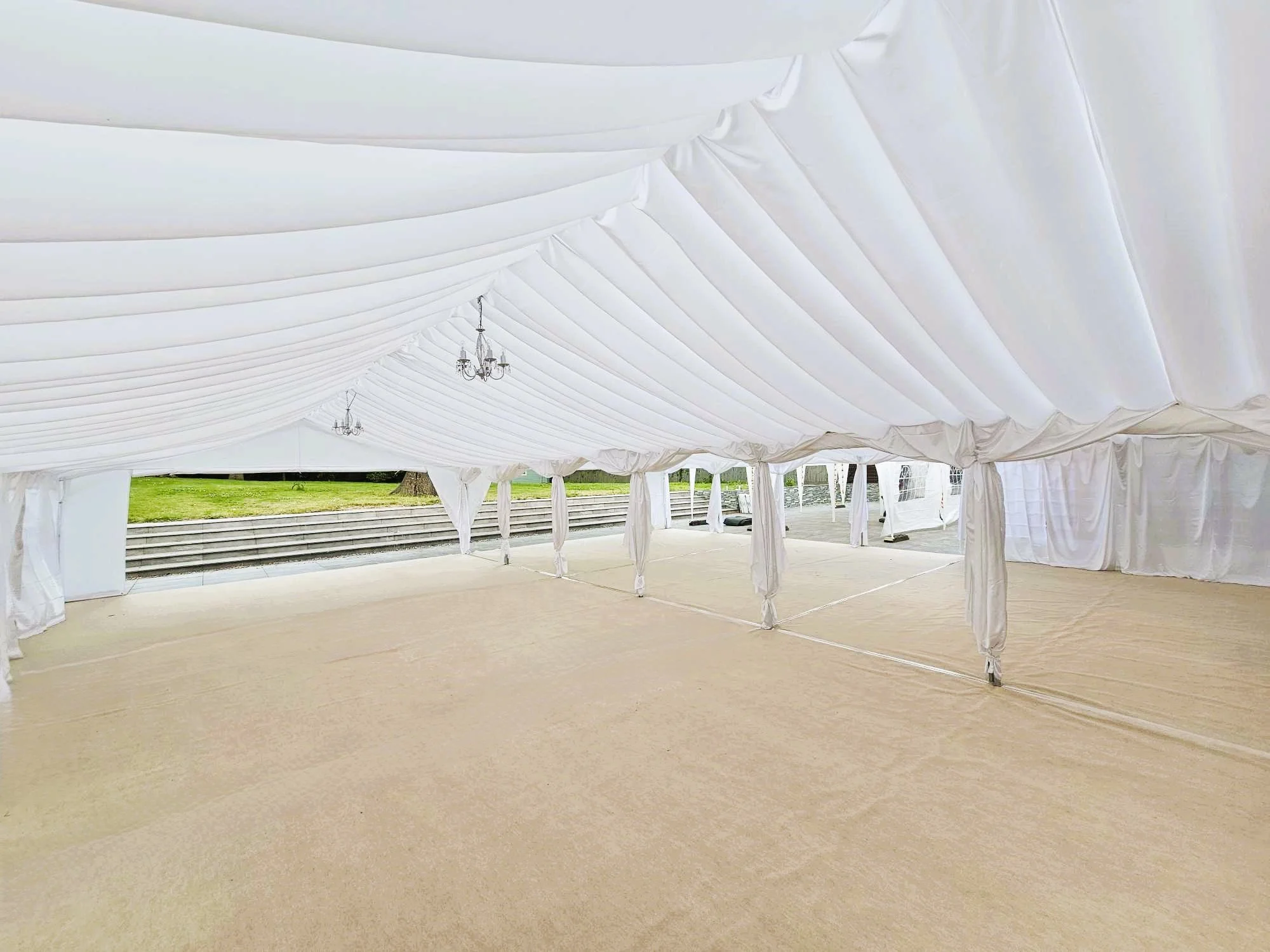 Luxury wedding marquee interior with draped lining, chandeliers and open event space