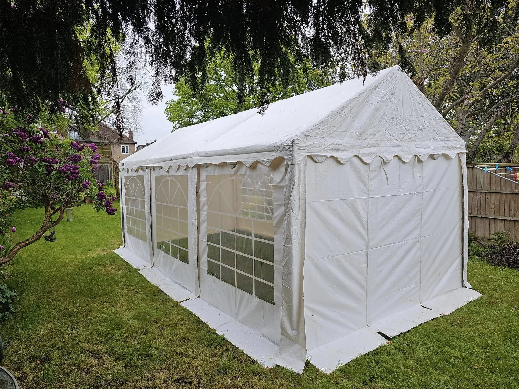 Garden party marquee setup with side panels and windows on grass lawn