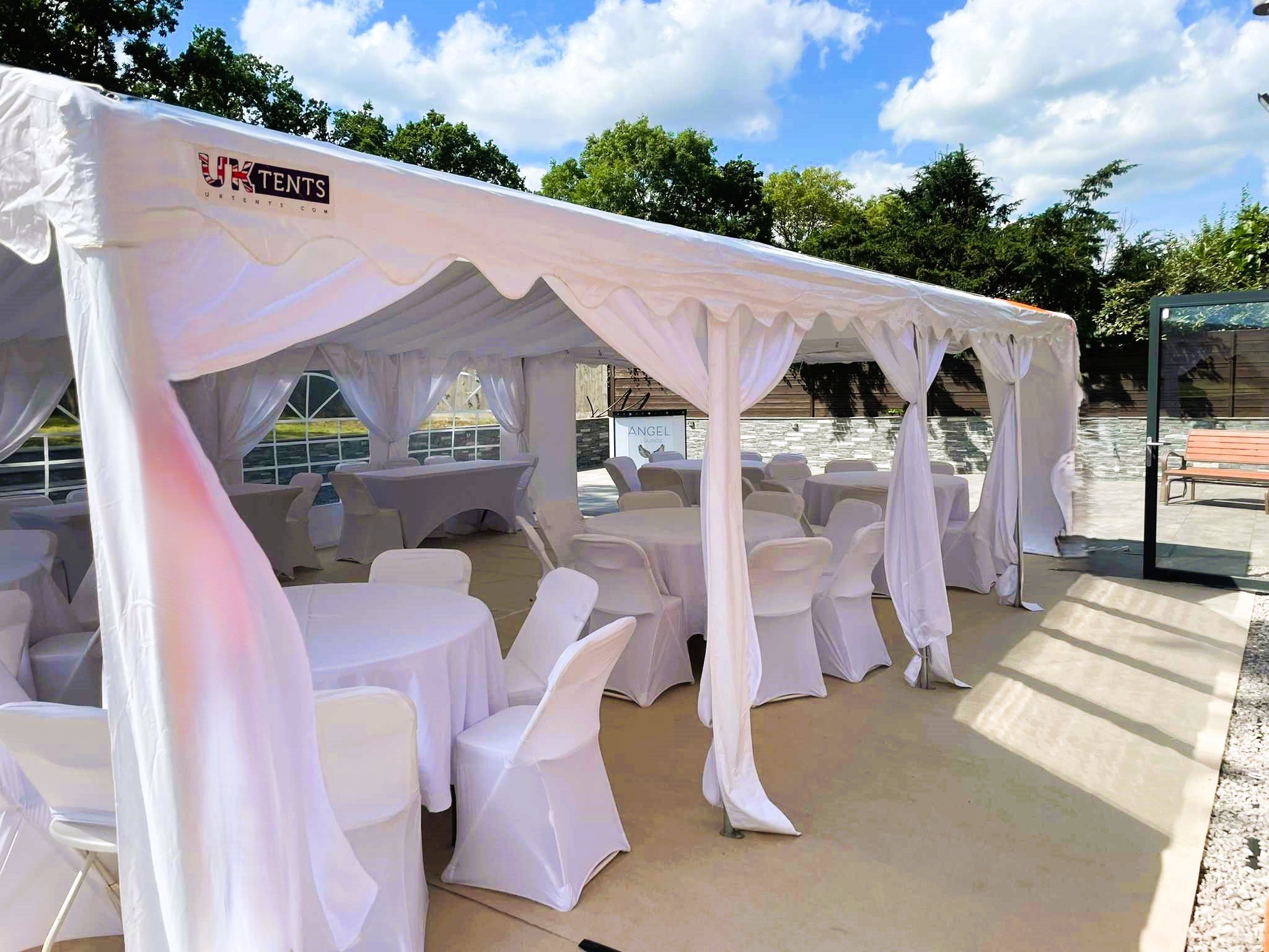 Wedding marquee setup with floral décor and draped ceiling by NK Marquees – marquee hire Milton Keynes and Bedfordshire