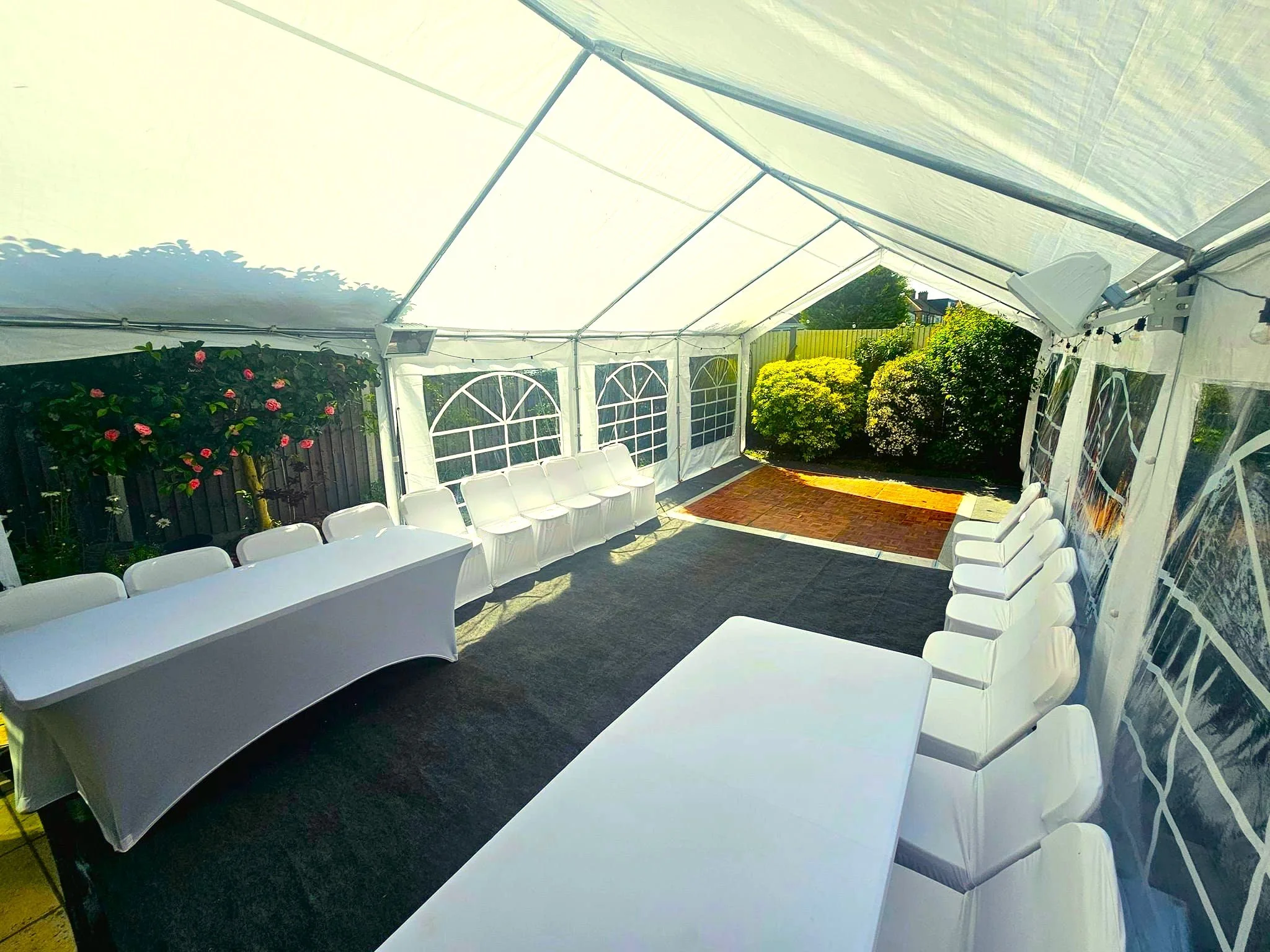 Marquee interior with tables, chairs, carpet flooring and window panels for event setup