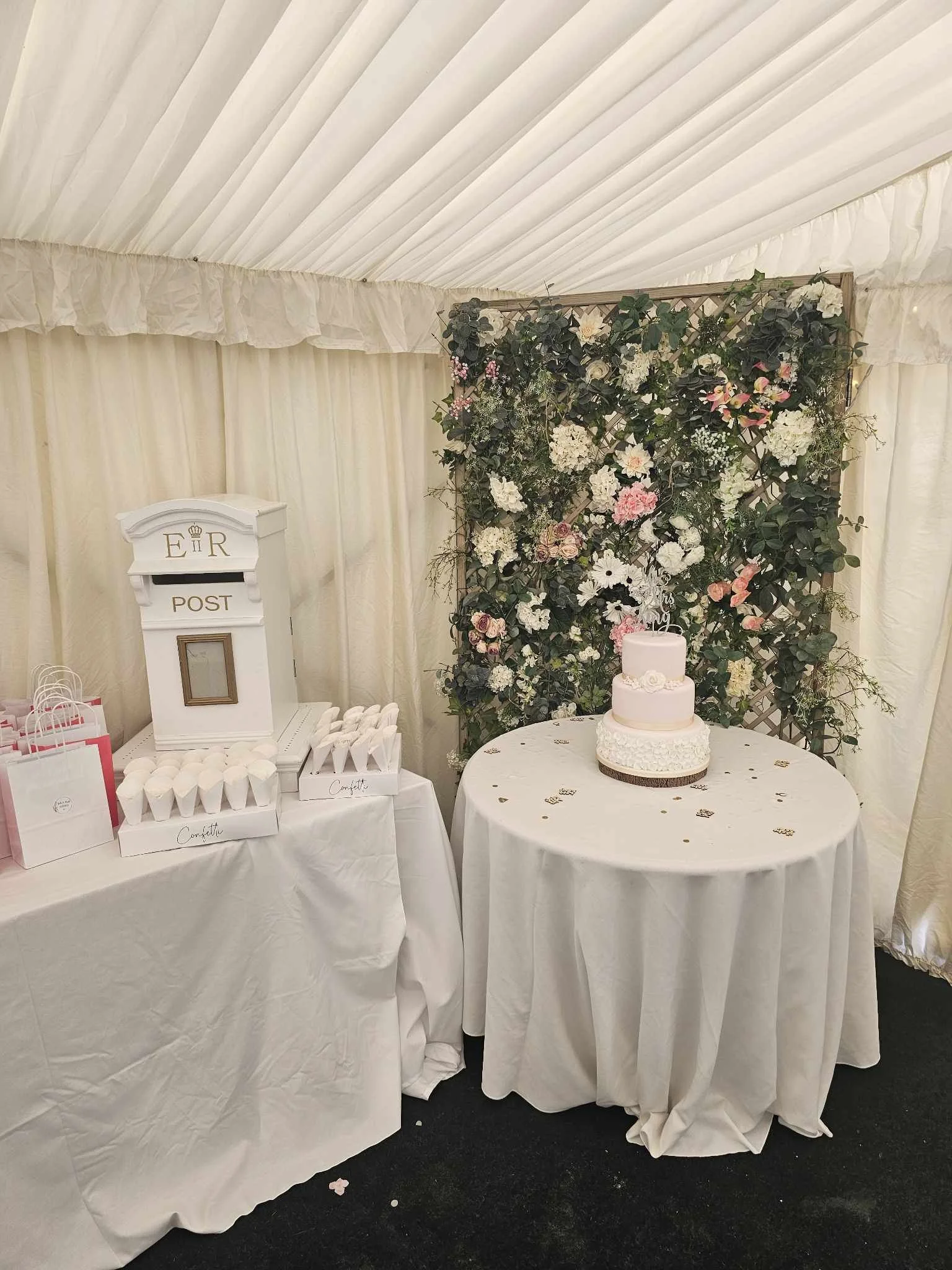 Wedding marquee interior with floral backdrop, cake table and styling details set up by NKMarquees