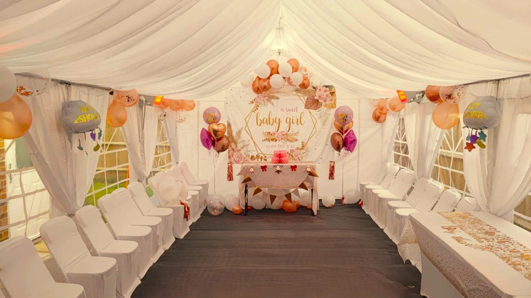Decorated party marquee interior with seating, balloons and baby shower setup