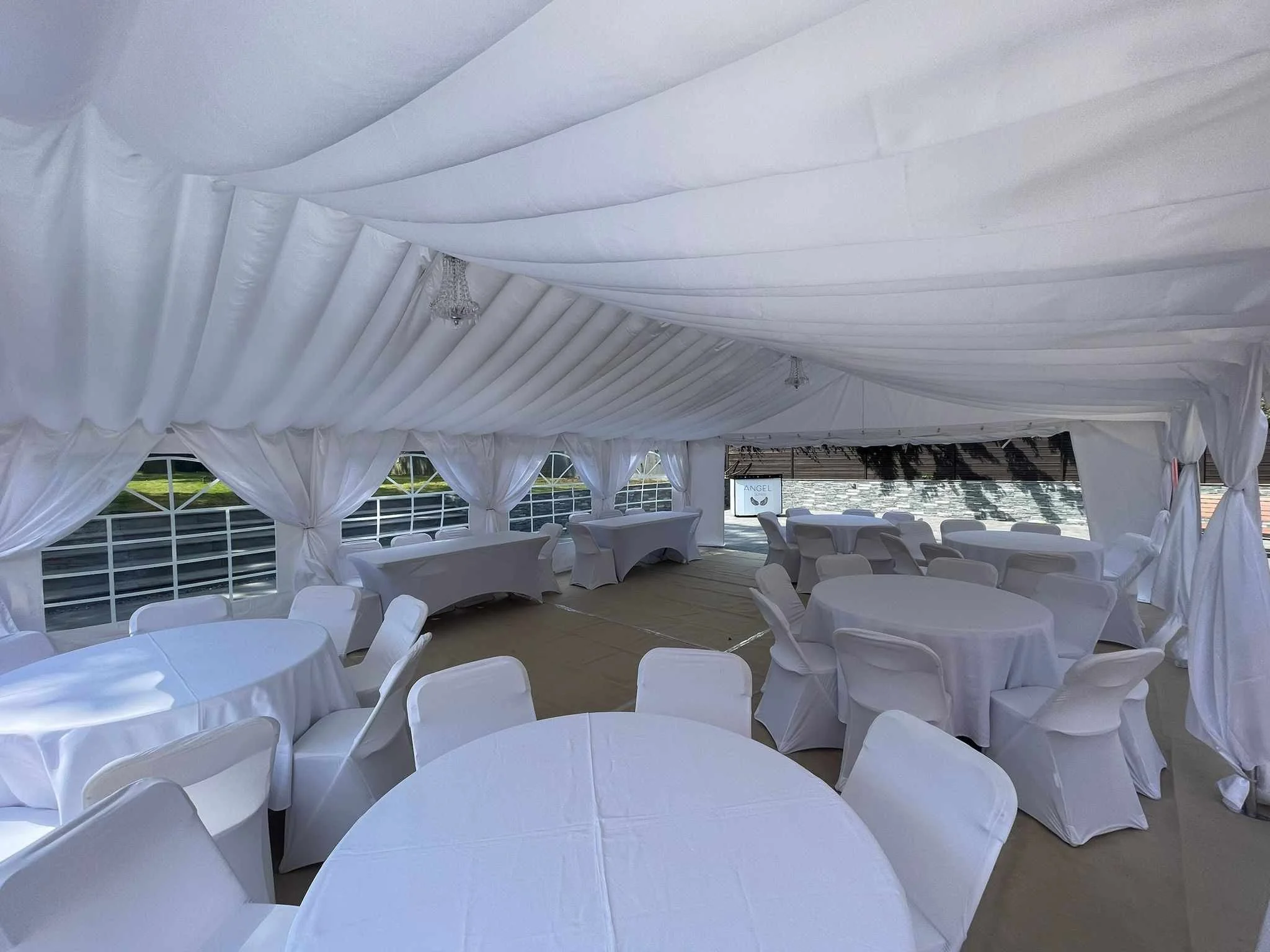 Elegant marquee interior with round dining tables and white chair covers for wedding reception