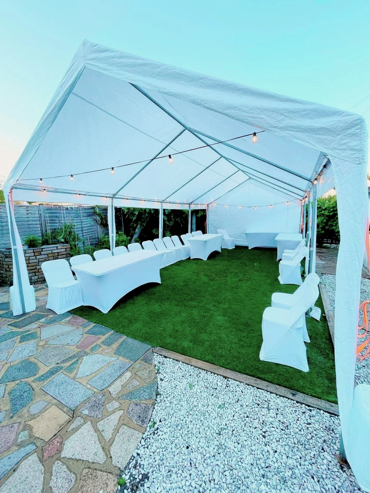 Corporate marquee setup with tables, chairs and festoon lighting for outdoor business event