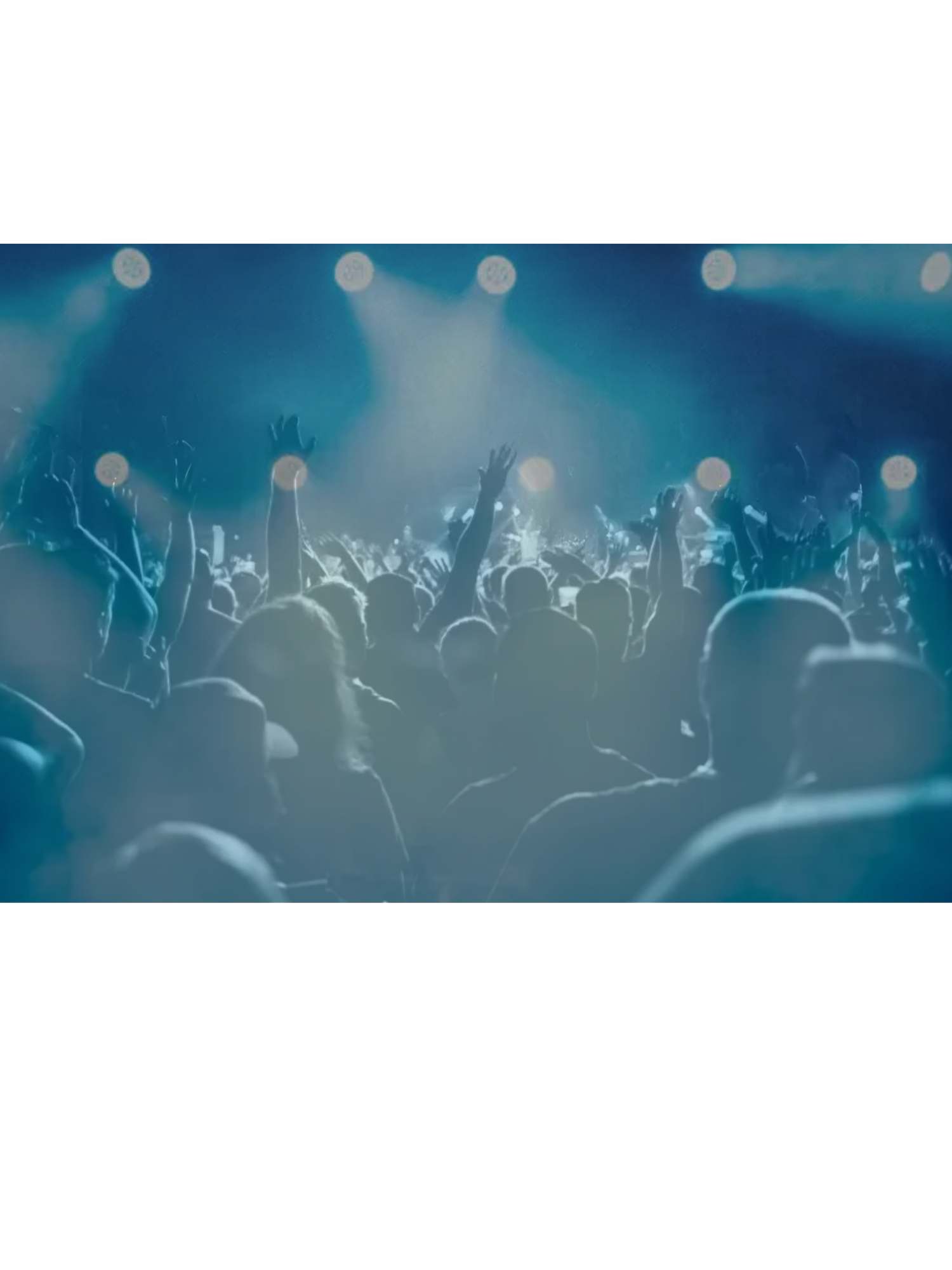 Crowd of people at a concert with hands raised, stage lights shining, and a blue hue.