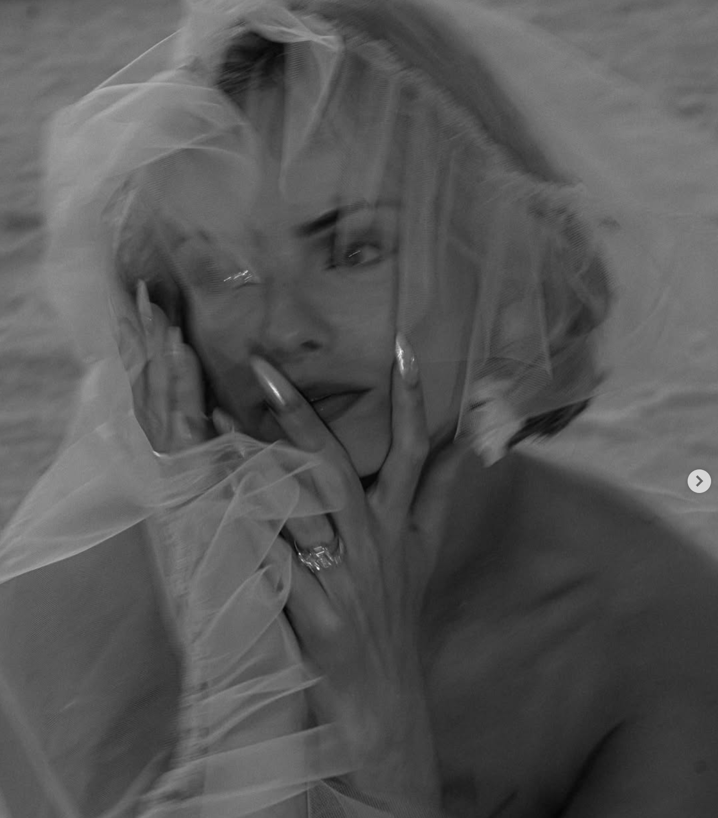 Black and white image of bride looking into the distance with a ruffle veil artfully arrange around her head