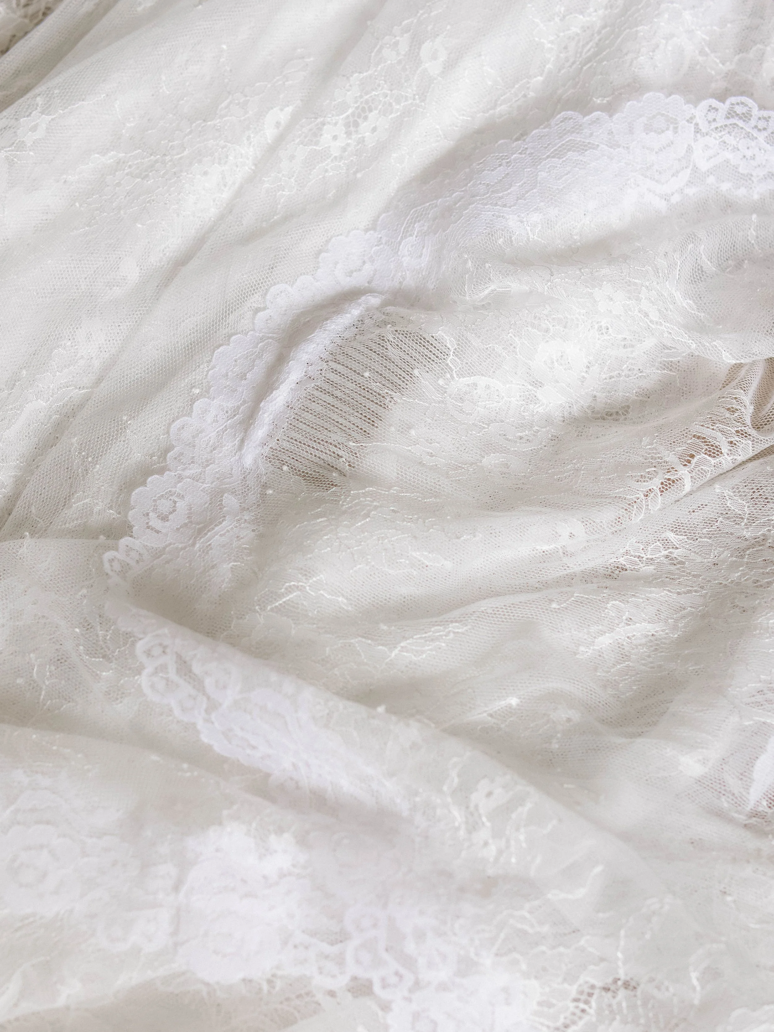 Closeup of a folded ivory lace veil with the veil comb visible through the top layer