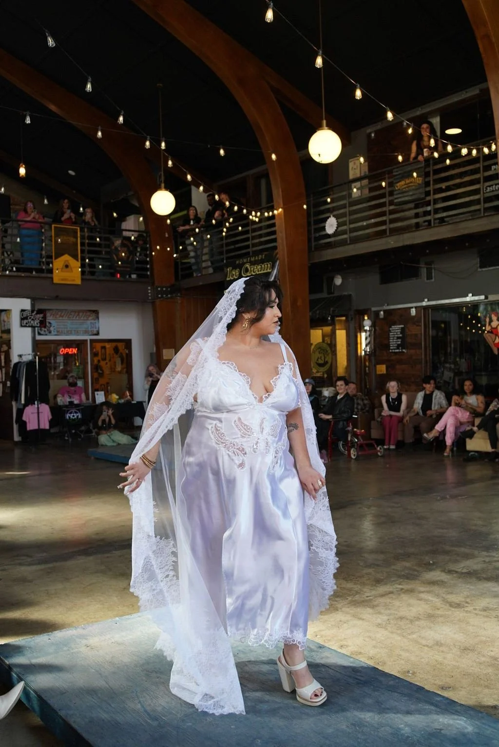 Woman walking down a runway wearing a lace and satin slip dress and a floor length mantilla veil with chantilly lace trim