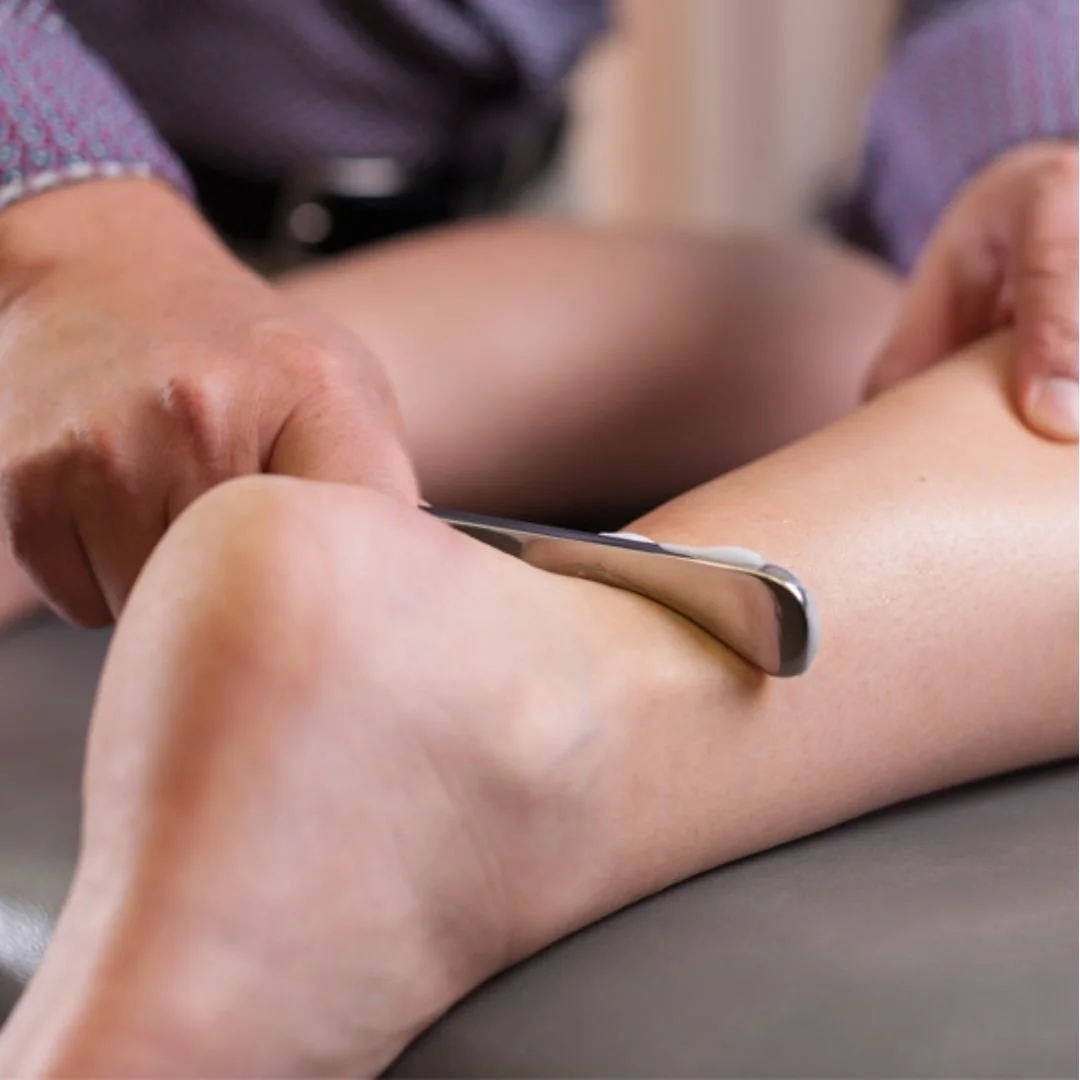 A person using a metal gua sha tool to massage and scrape the skin on their arm.