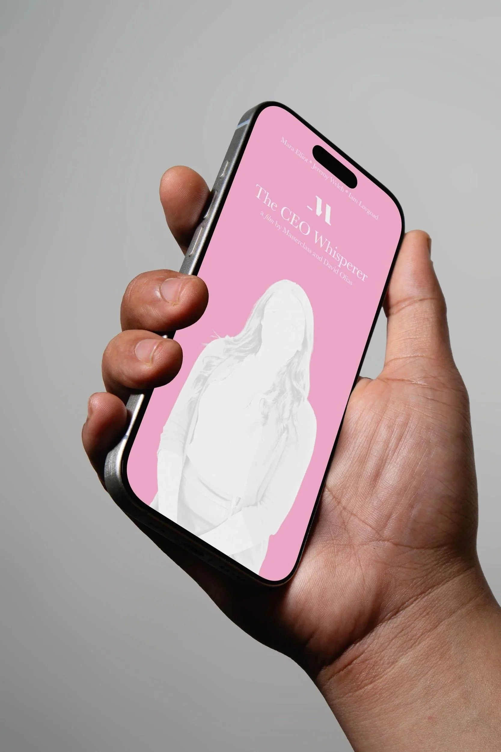 A hand holding a smartphone displaying the movie poster for "The CEO Whisperer" with a pink background and white illustration of a woman with long hair.