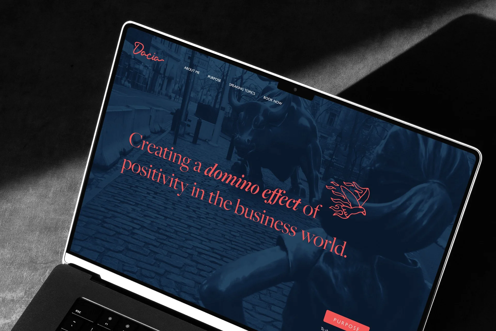 Laptop screen displaying a website titled 'Dacia' with menu options and a background image of a sculpture of a bull on a cobblestone street, overlayed with the text 'Creating a domino effect of positivity in the business world'.
