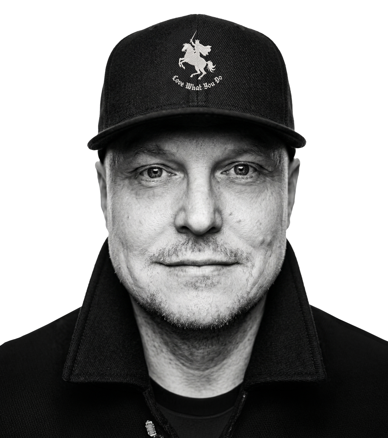 Black and white portrait of a man wearing a baseball cap with a unicorn and the words "Love What You Do" embroidered on it.