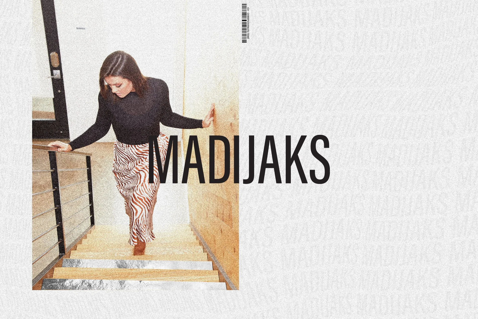 A woman with shoulder length brown hair wearing a black top and striped red and white pants ascending a staircase indoors.