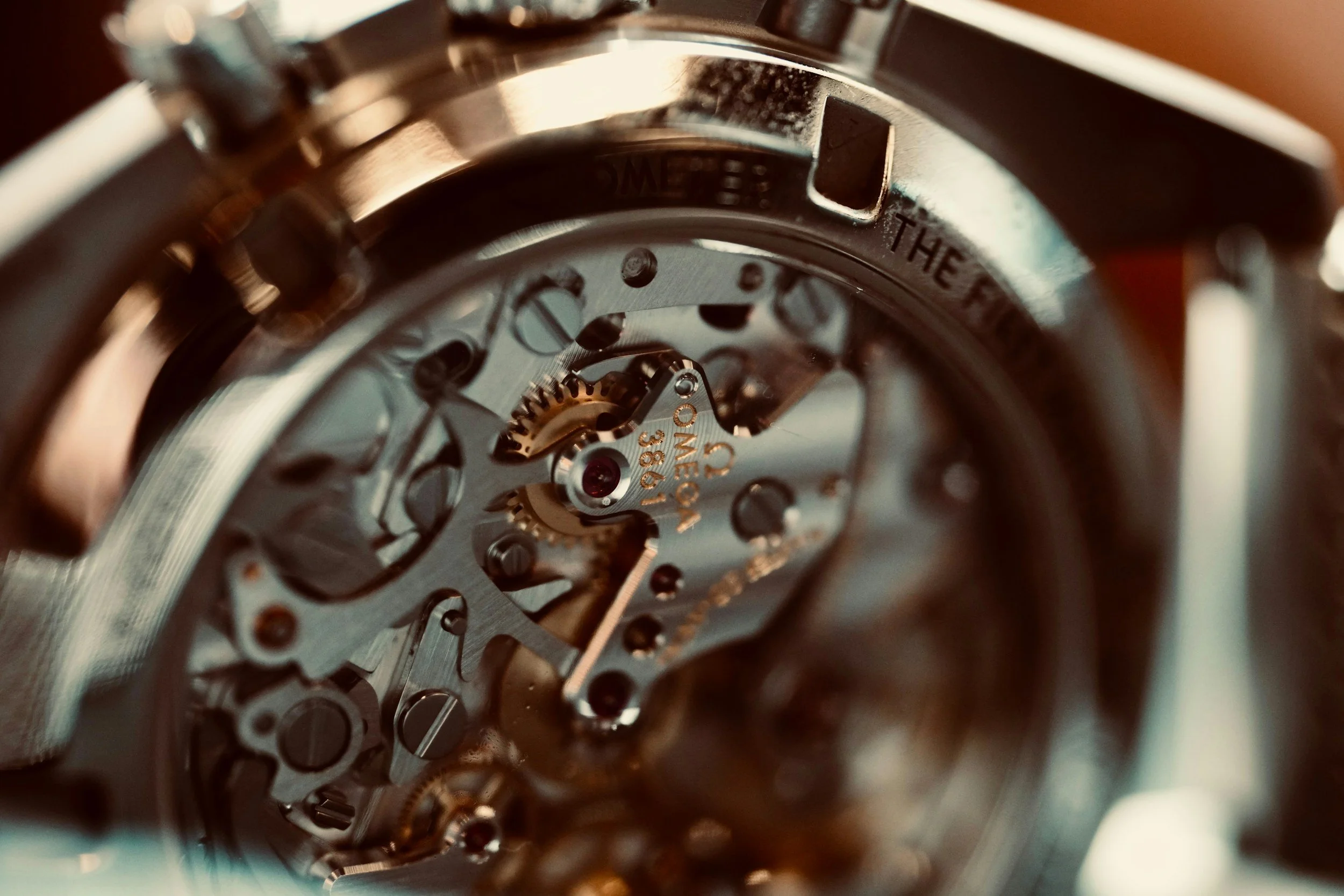 Close-up view of the internal mechanical components of a watch movement, showing gears, screws, and engraved details.