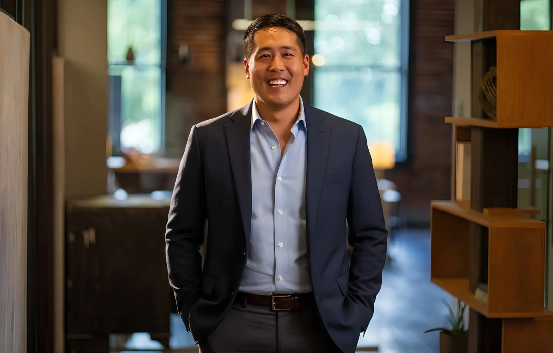 Smiling man in a business suit standing in a modern office space.