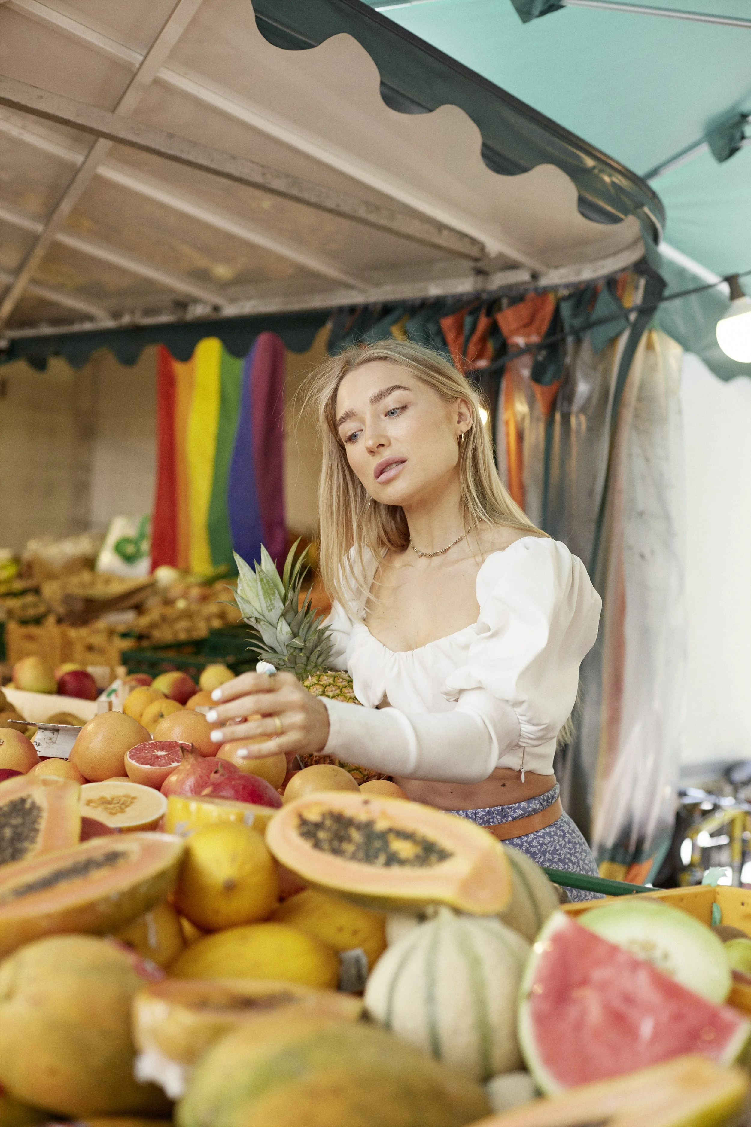 Junge Frau kauft frisches Obst auf einem Markt, Sinnbild für bewusste und ganzheitliche Ernährung.