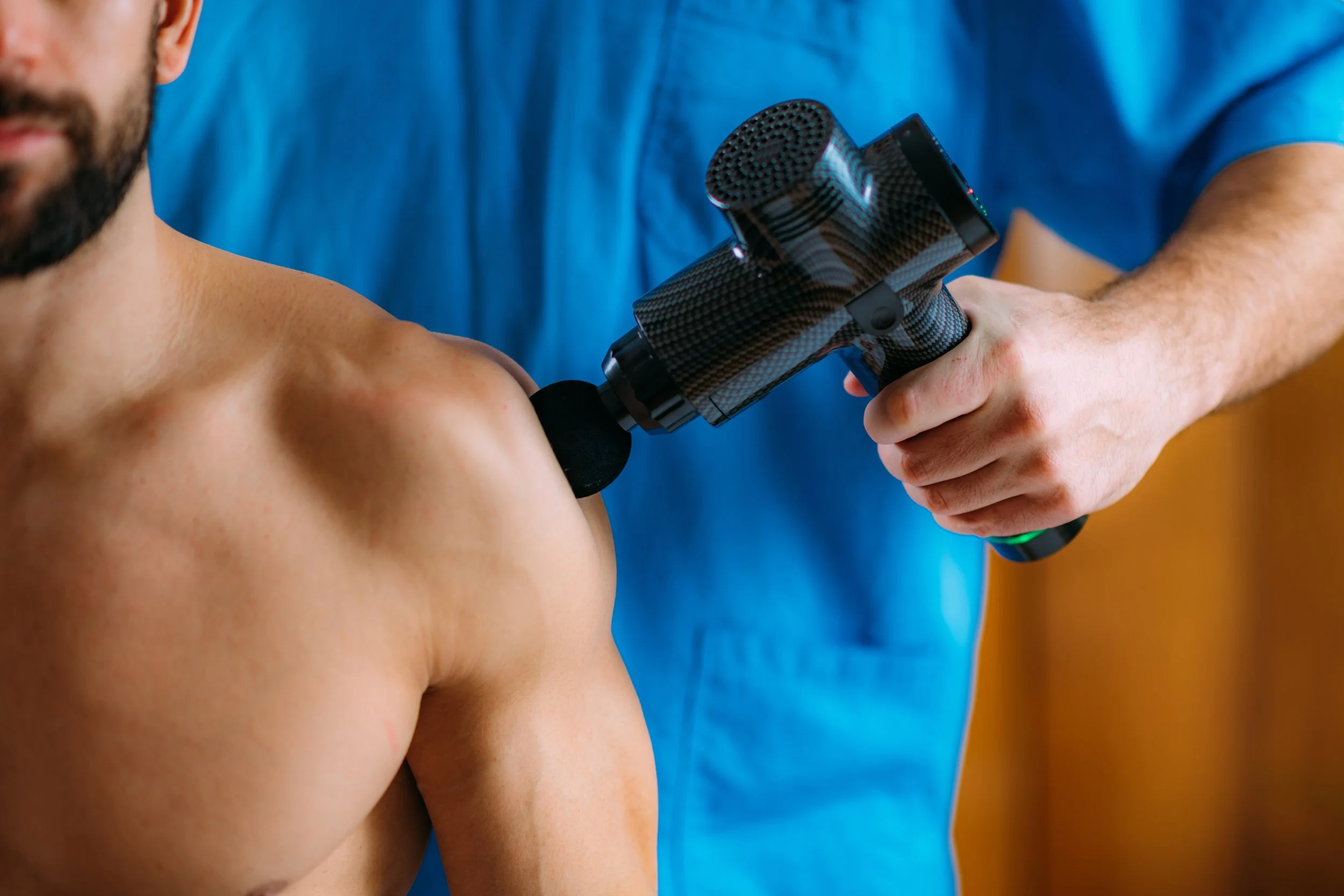 man receiving massage gun, theragun, hypervolt