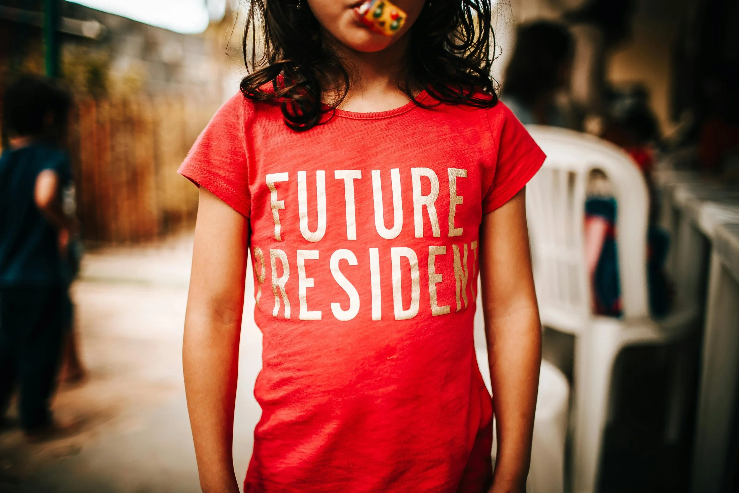 Young girl wearing a red t-shirt with the words 'FUTURE PRESIDENT' printed on it.