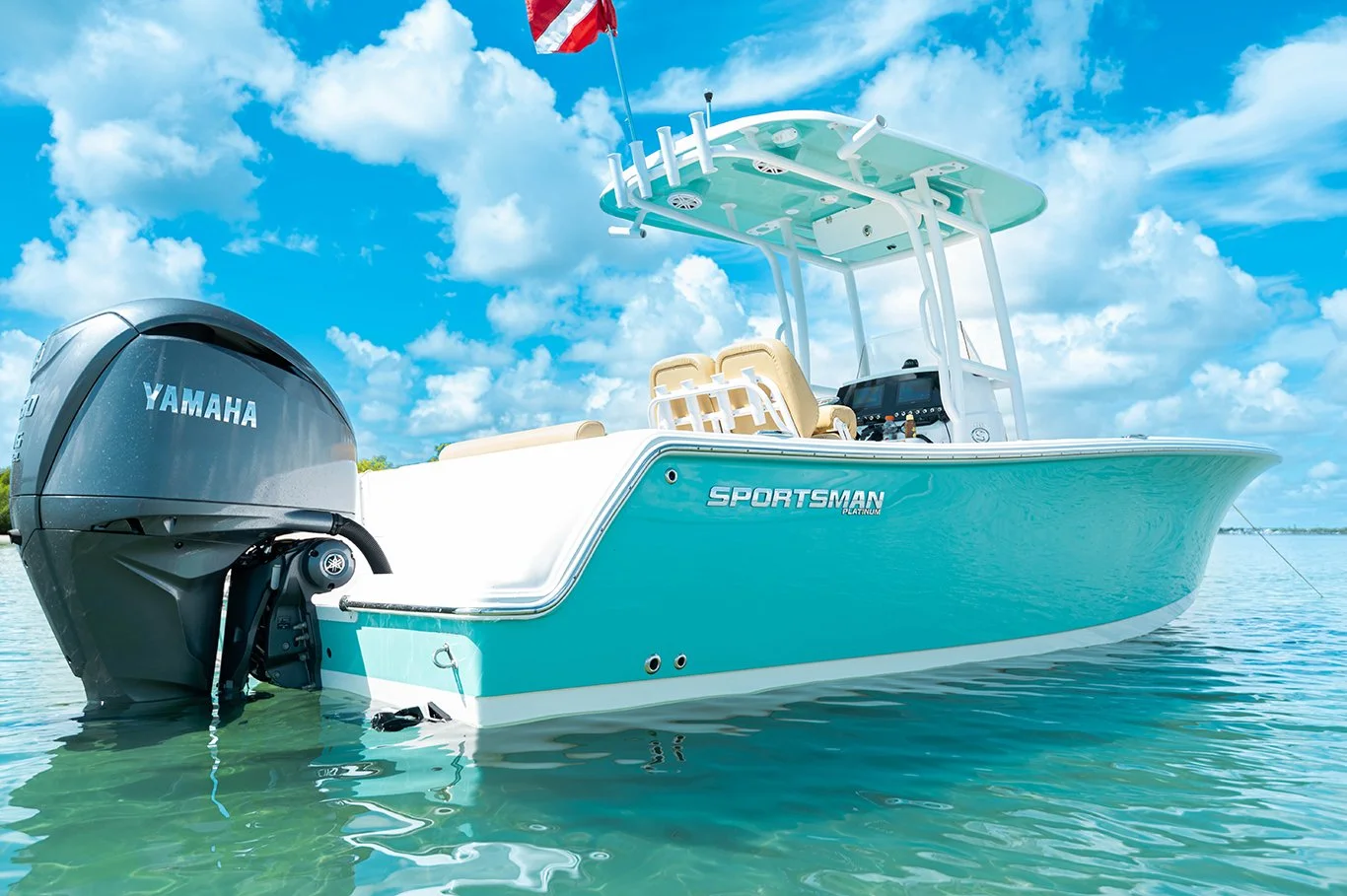 A light blue and white Sportsman boat with a Yamaha outboard motor, floating on calm water under a blue sky with clouds.