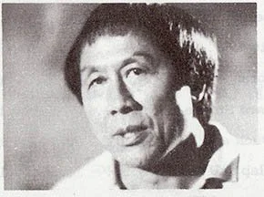 Black and white photograph of a man with short hair, dressed in a suit, looking slightly to the side.
