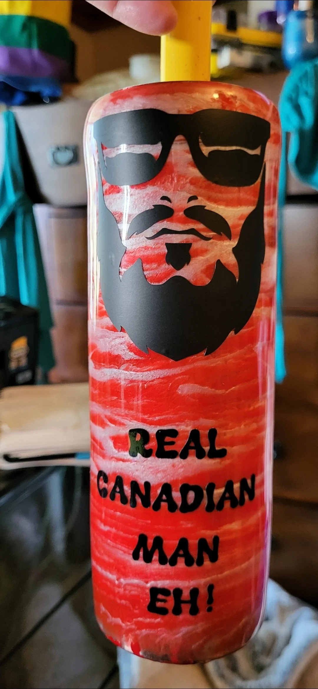 A red and white marbled tumbler with a black graphic of a bearded man wearing sunglasses and the text 'Real Canadian Man Eh!' in black.