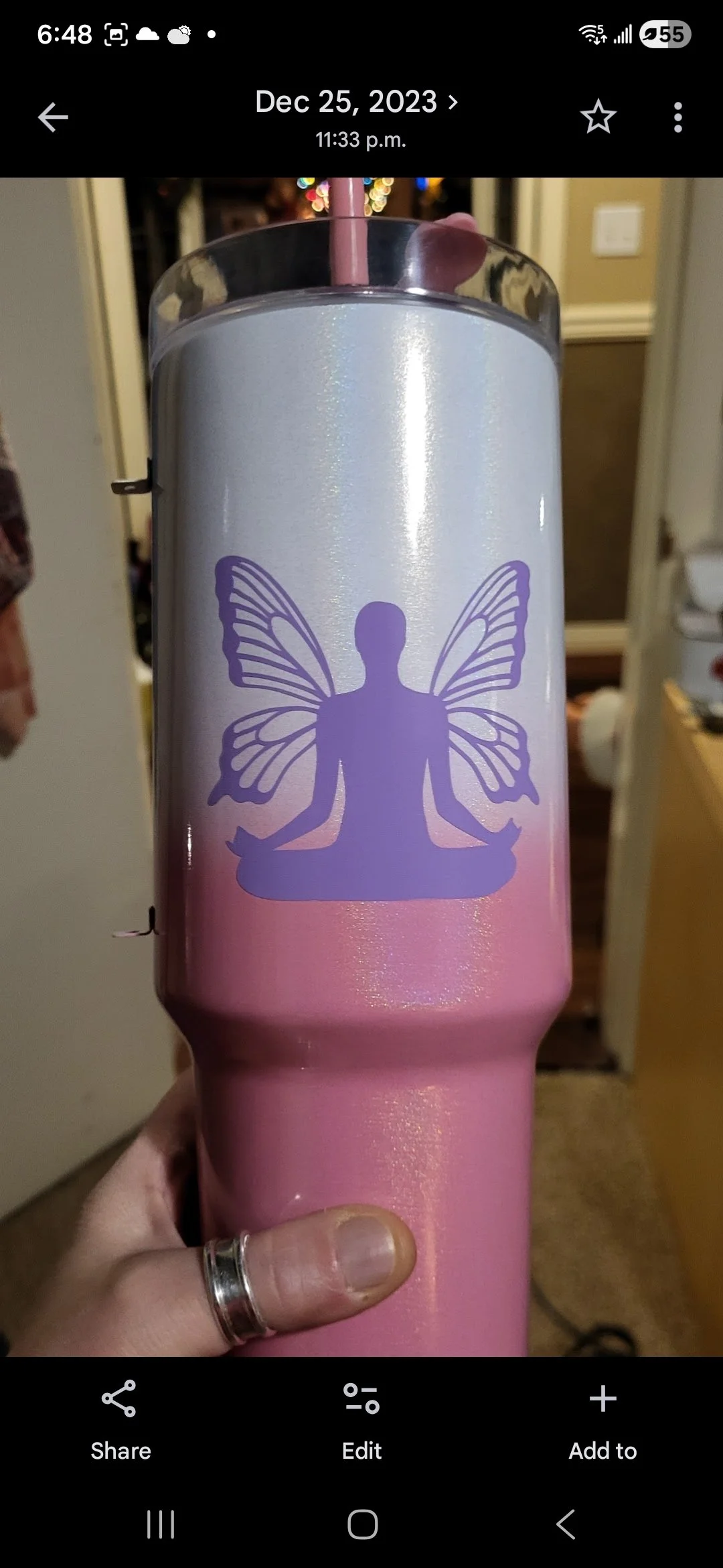 A pink tumbler with a purple silhouette of a person in a meditative pose, with butterfly wings attached to their back.