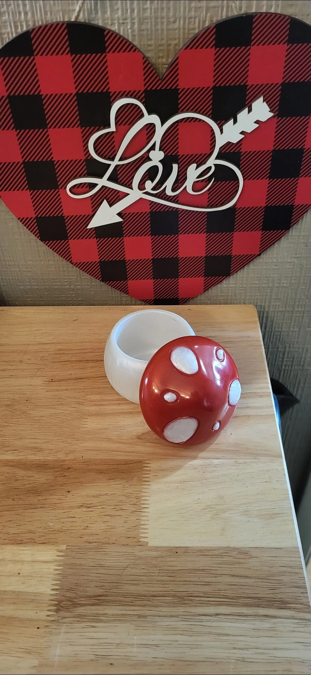 Decorative red and white mushroom, a small white bowl, and a heart-shaped wall hanging with a plaid pattern and the word "Love" with an arrow.