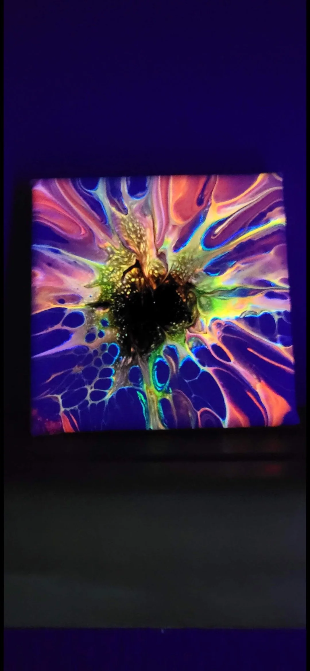 Colorful abstract painting with vibrant splashes of purple, green, yellow, and blue on a black background