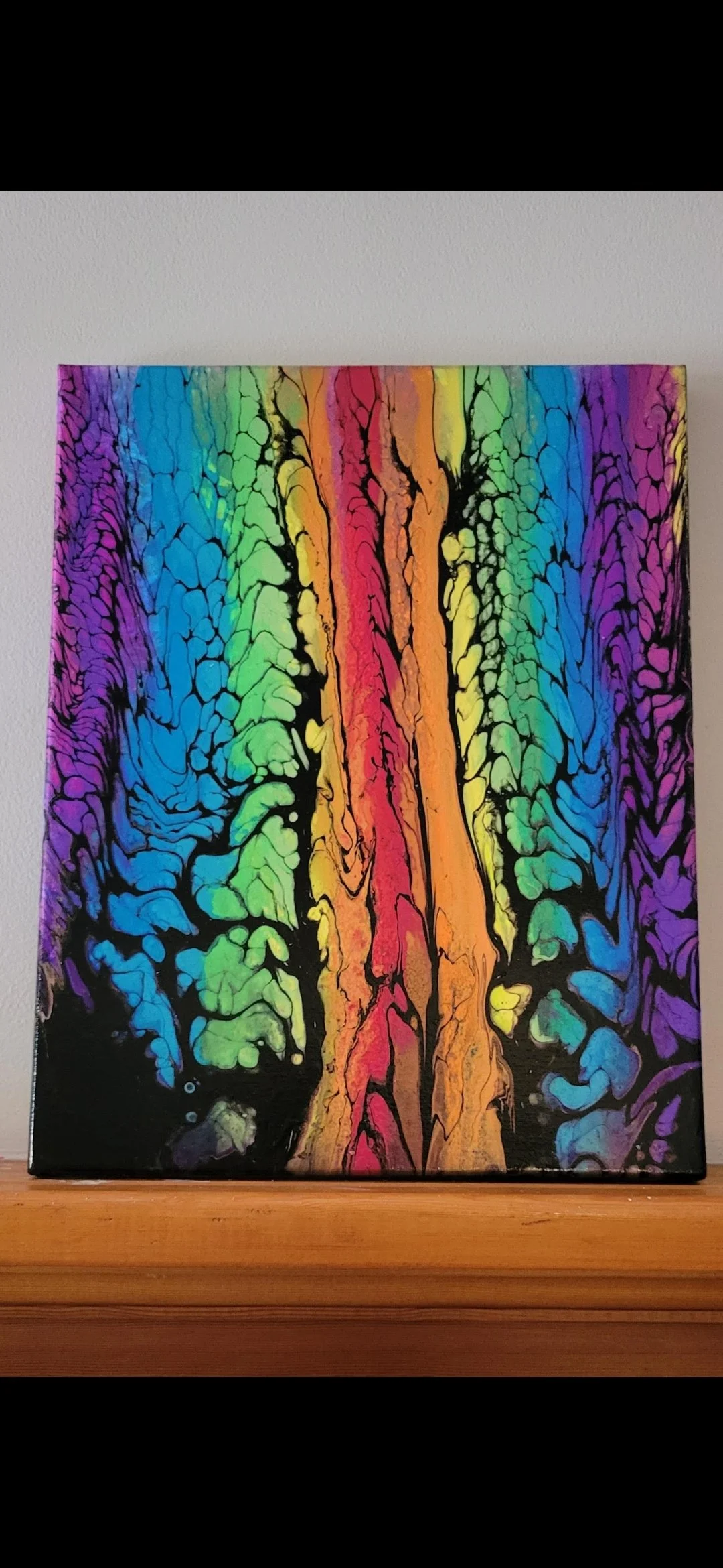 Abstract painting with vibrant rainbow colors and black accents, resembling a flowing, organic pattern.